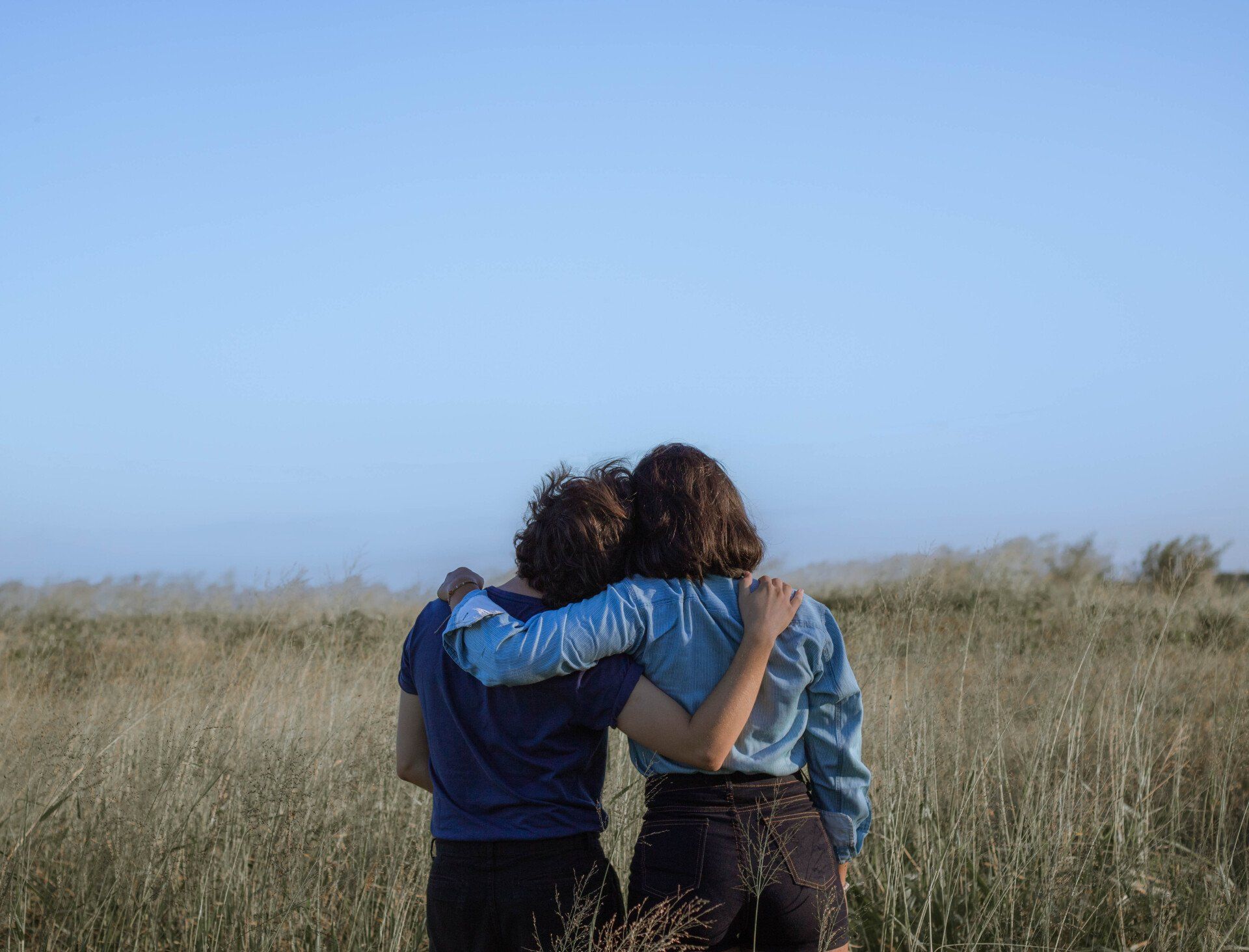 Two people standing in a field looking towards to the horizon.