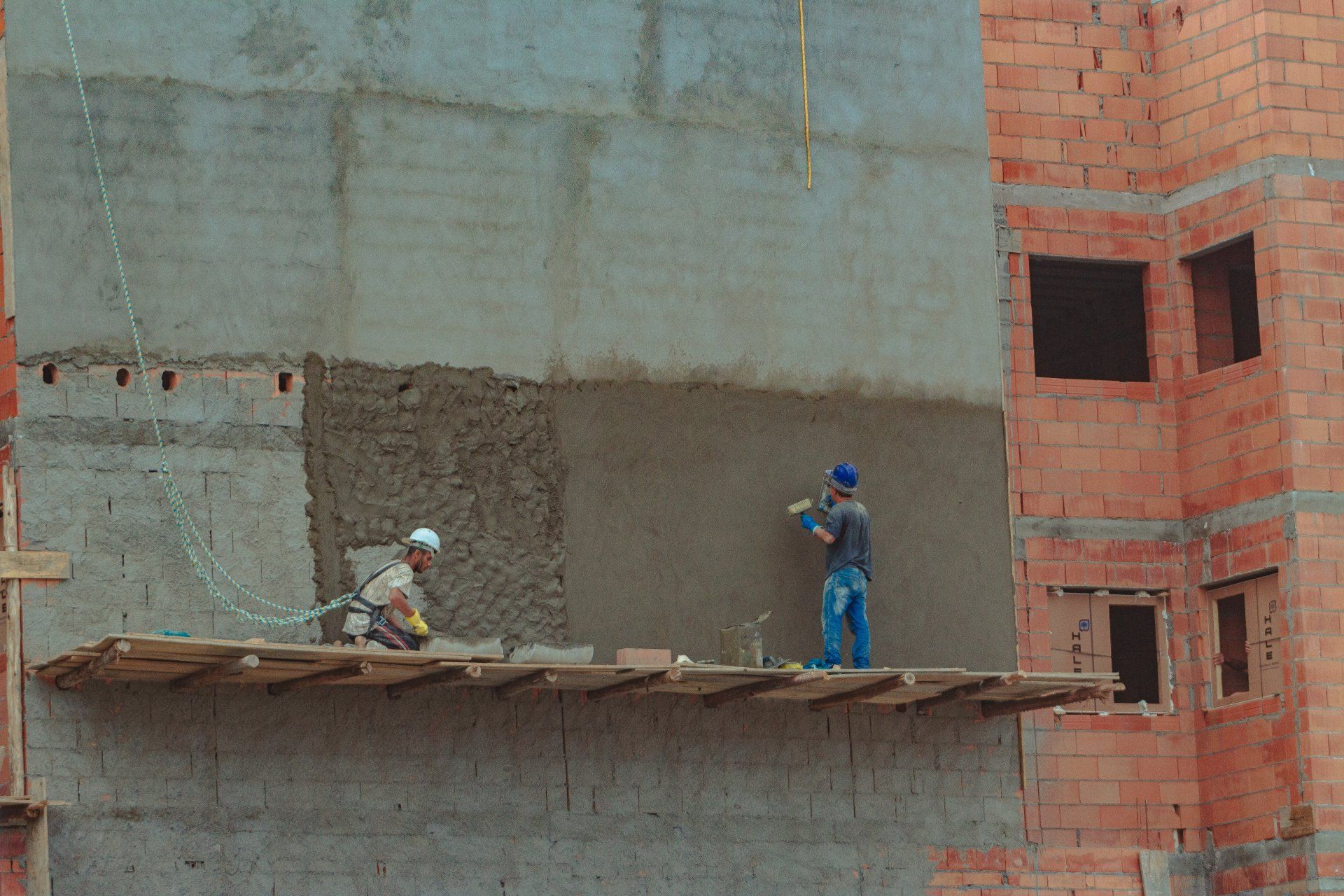 A man using a trowel to smooth and finish a concrete wall surface.