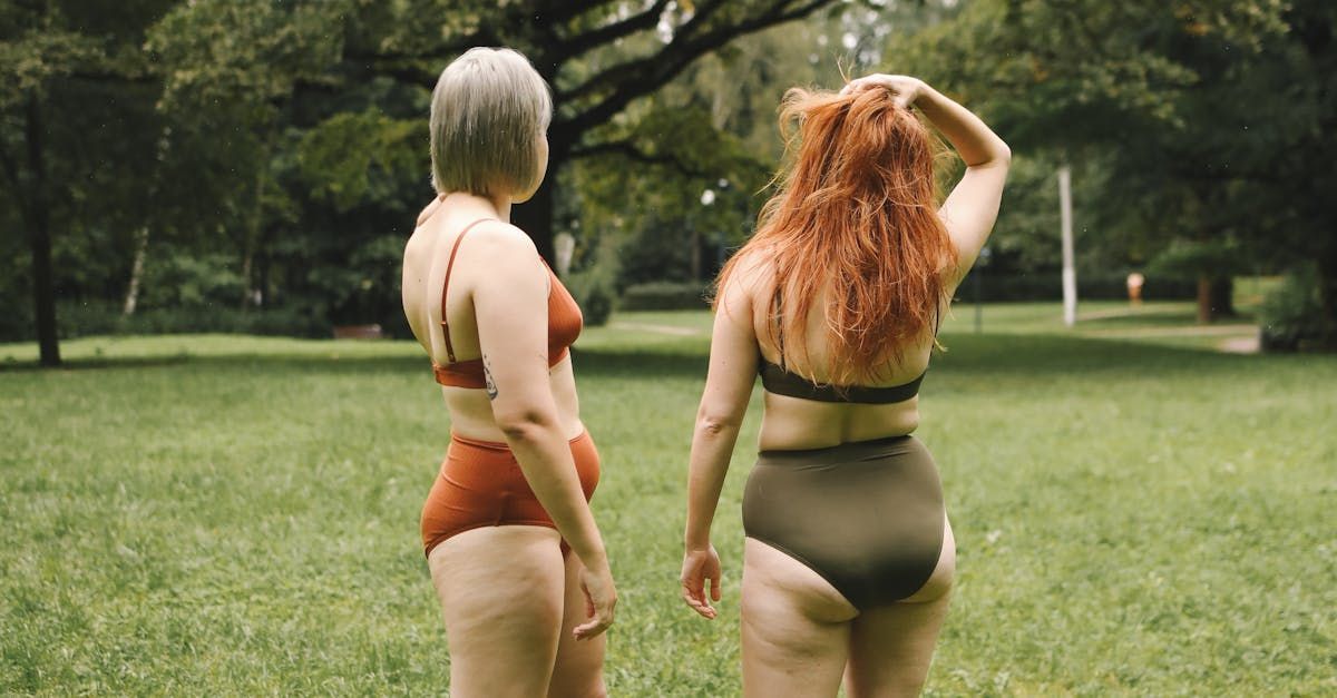 Two women in bikinis are standing next to each other in a park.