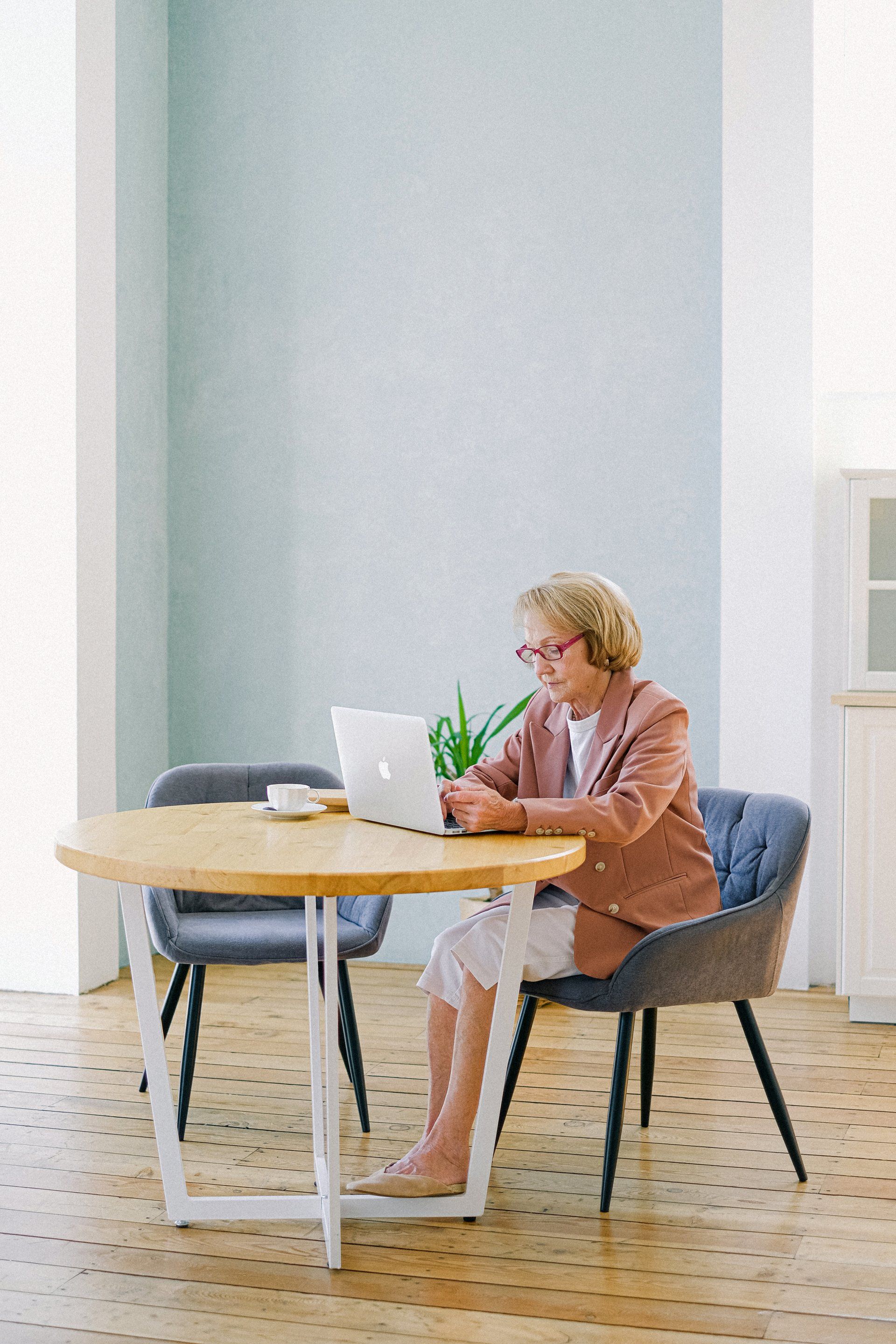 A woman is sitting at a table using a laptop computer.