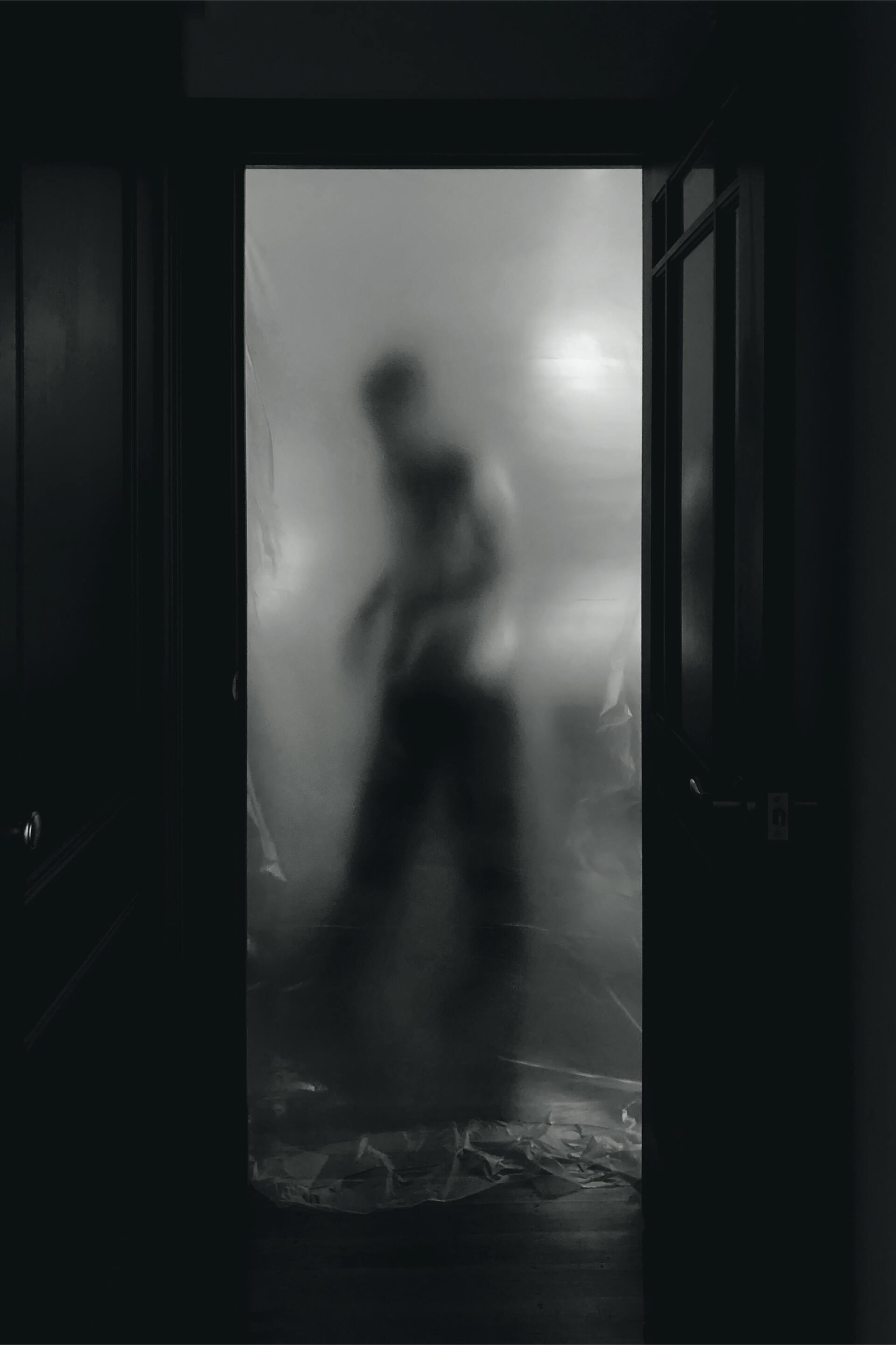 A silhouette of a person standing in a doorway in a dark room.