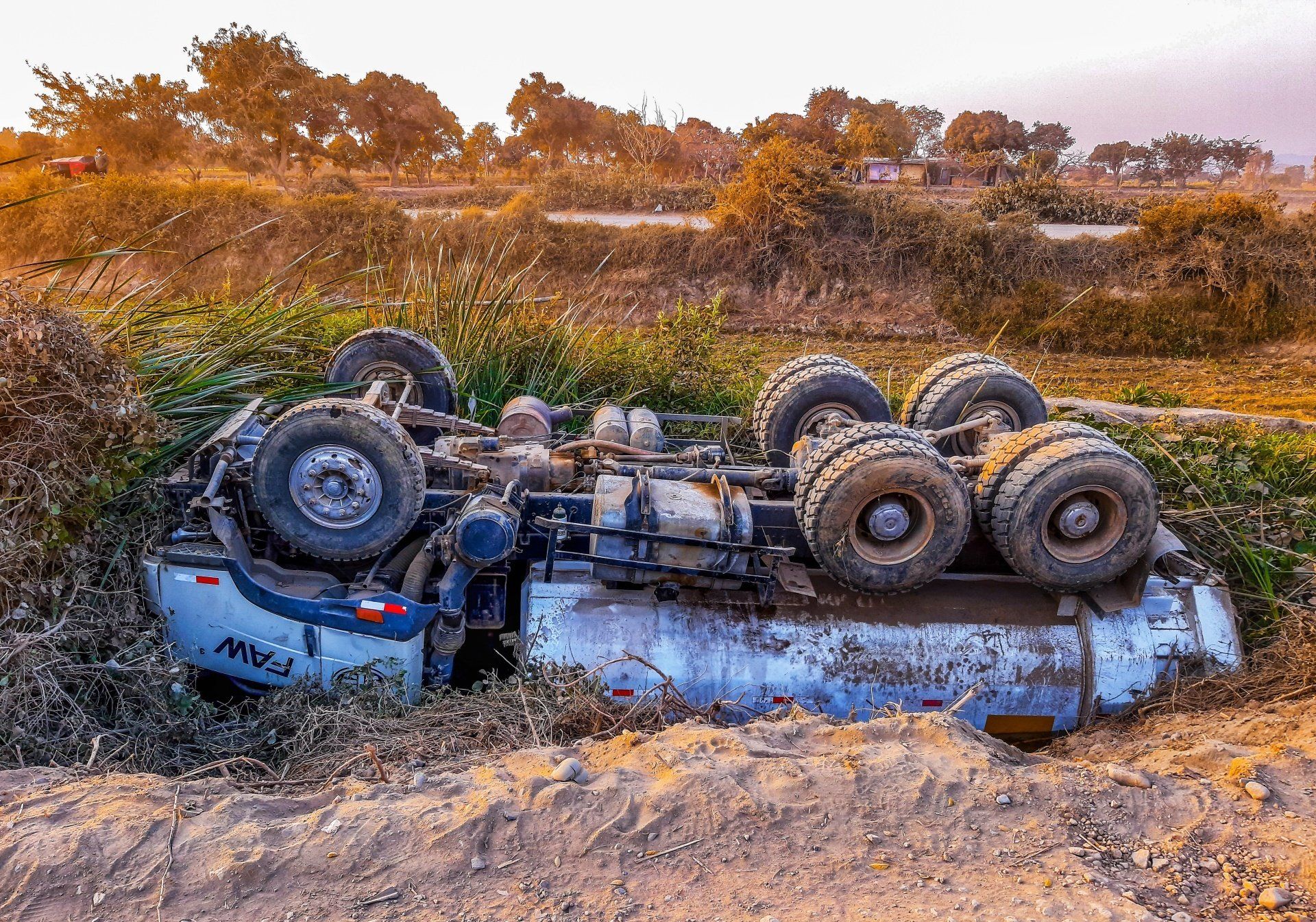 A truck has fallen over on its side in a field.