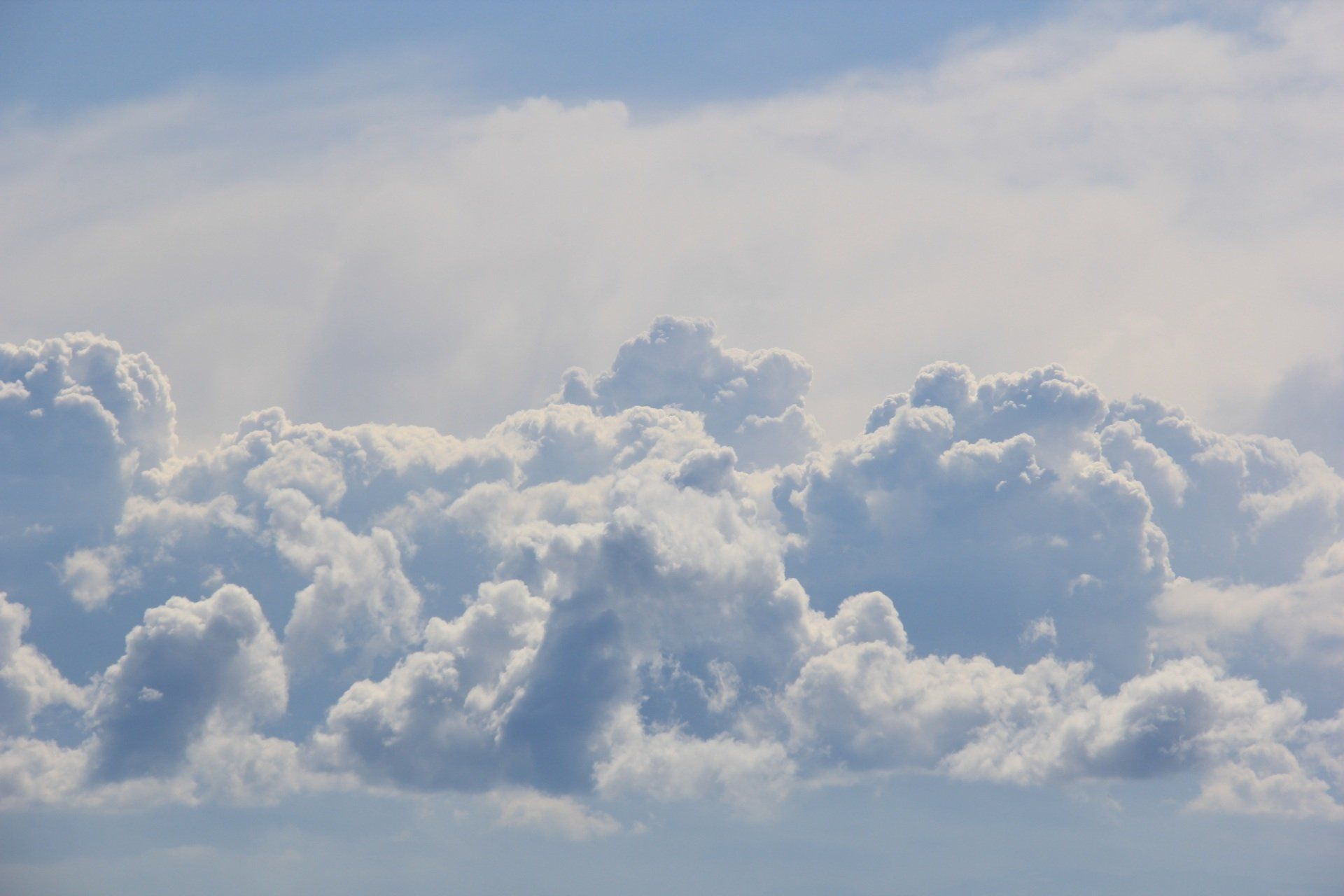 A view of clouds from an airplane window on a sunny day.