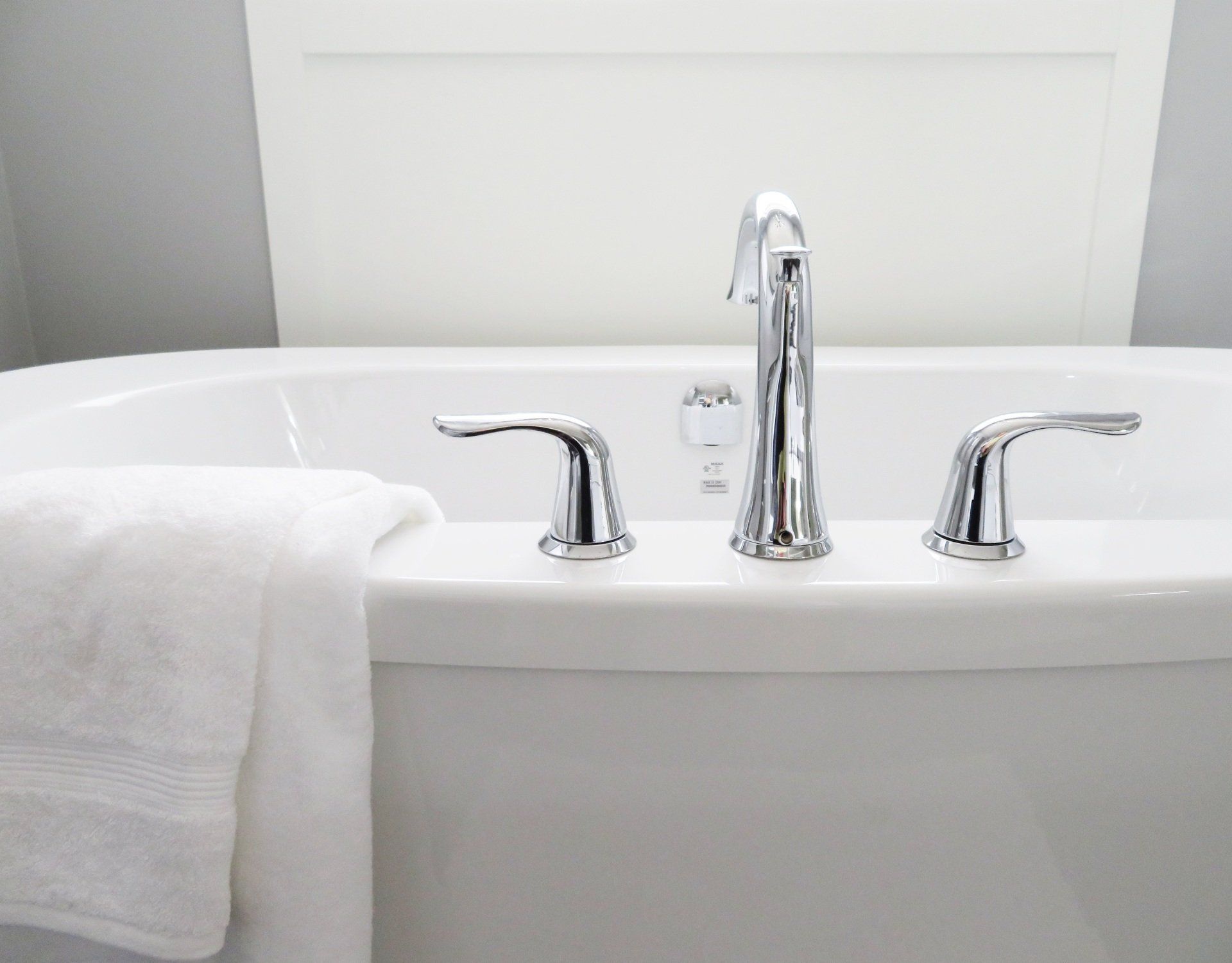 a bathtub with chrome handles and a towel on the side