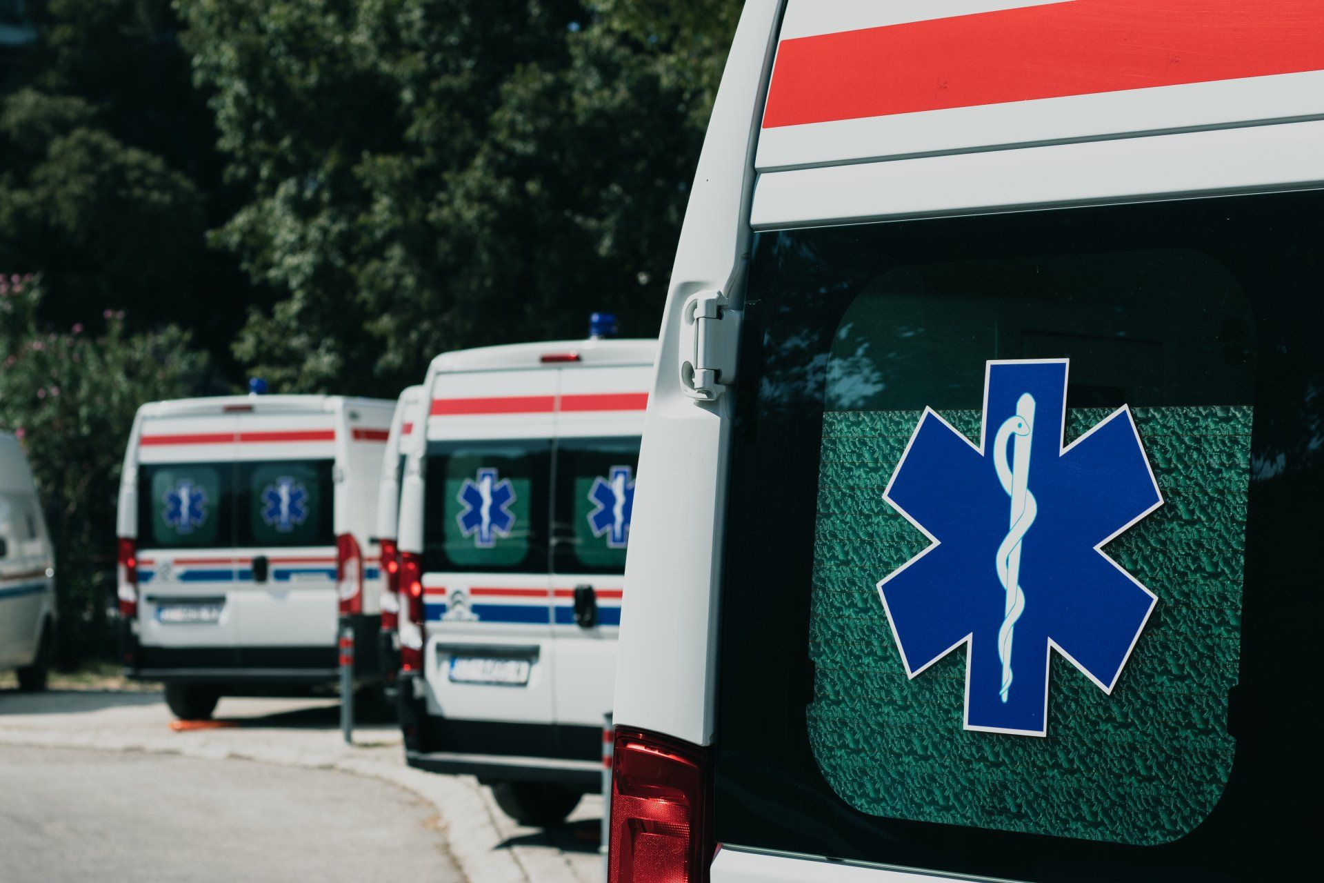 A row of ambulances are parked on the side of the road.