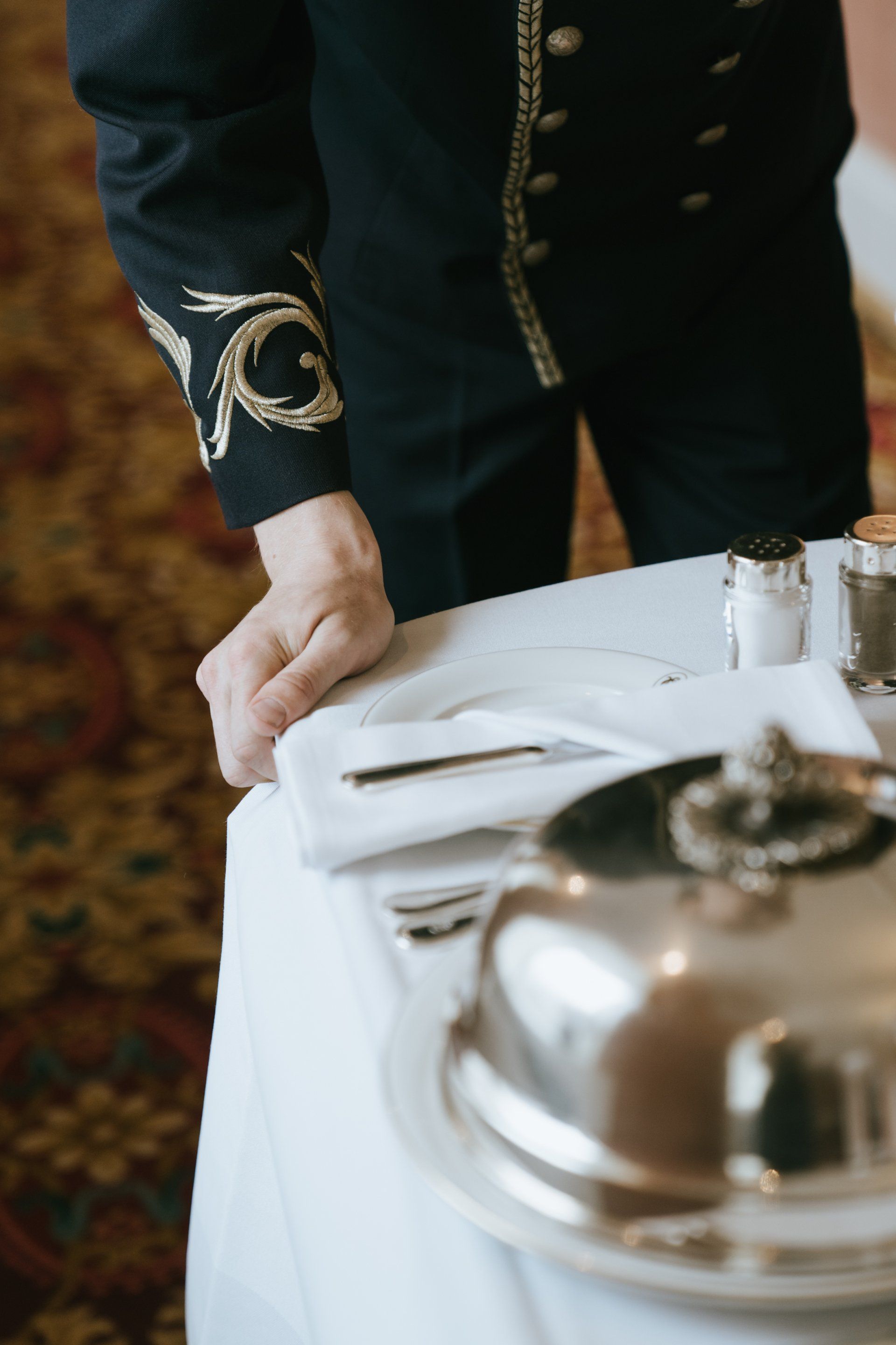 A man in a black jacket is standing at a table with a silver tray on it.