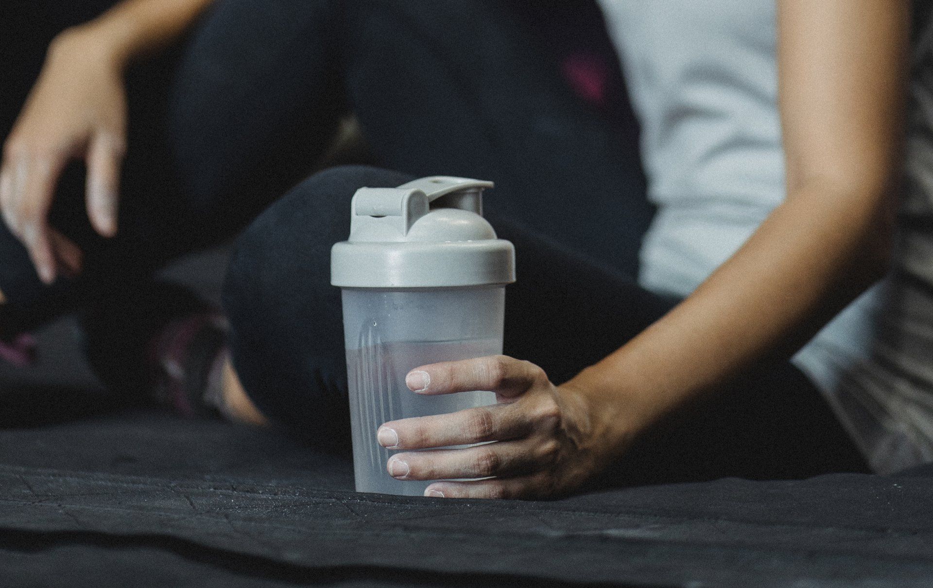 A woman is sitting on a mat holding a shaker in her hand.