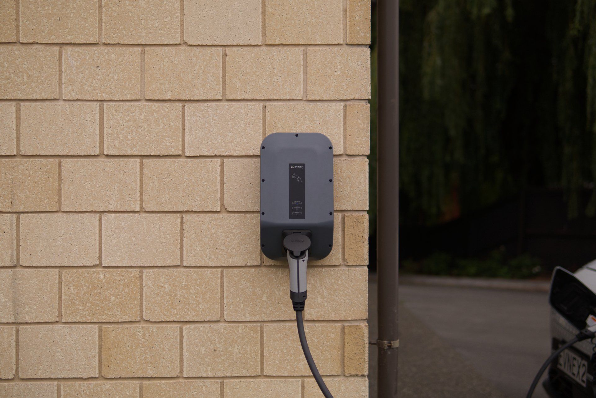 An electric car is being charged on a brick wall.