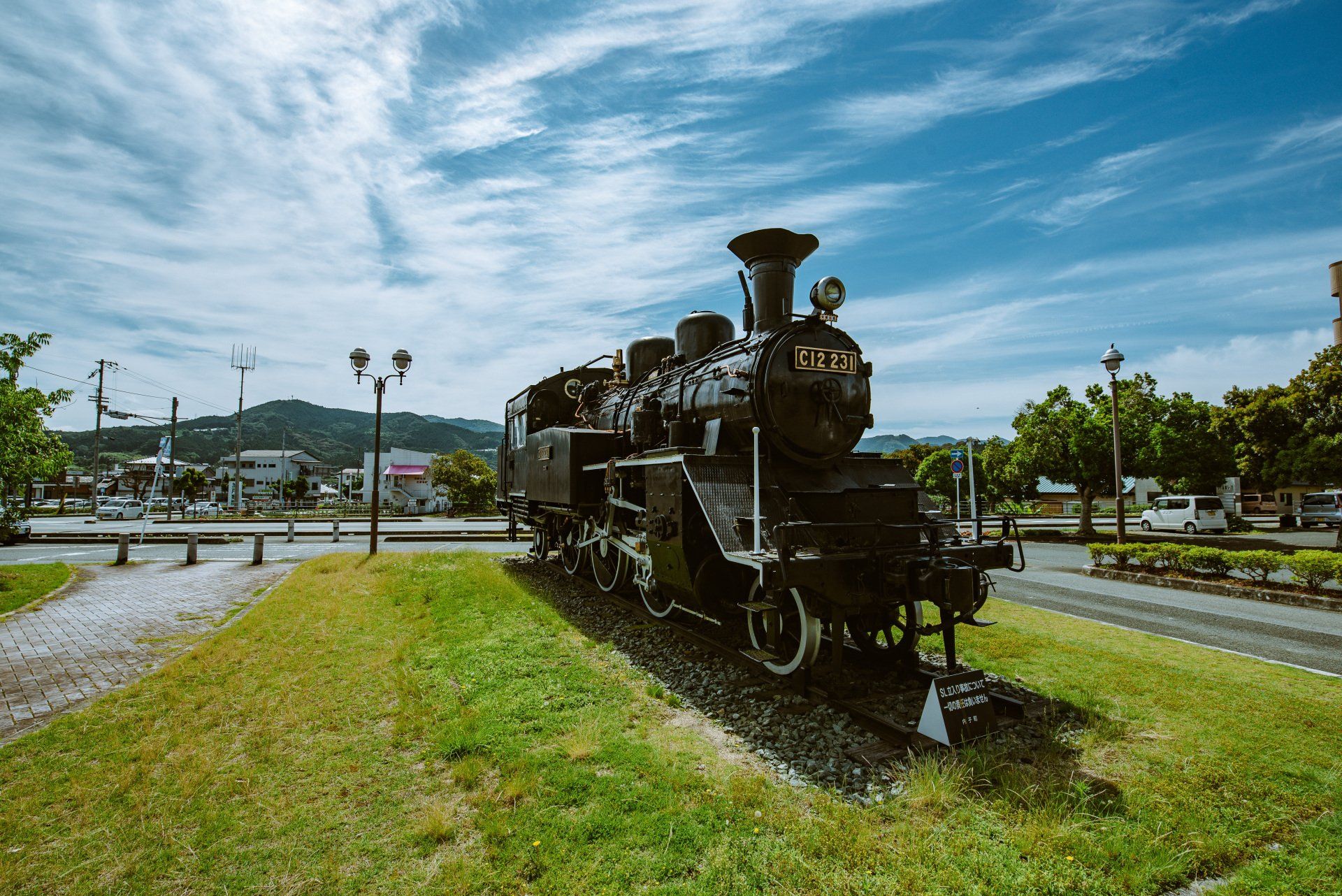 An old train engine is sitting on top of a lush green field.