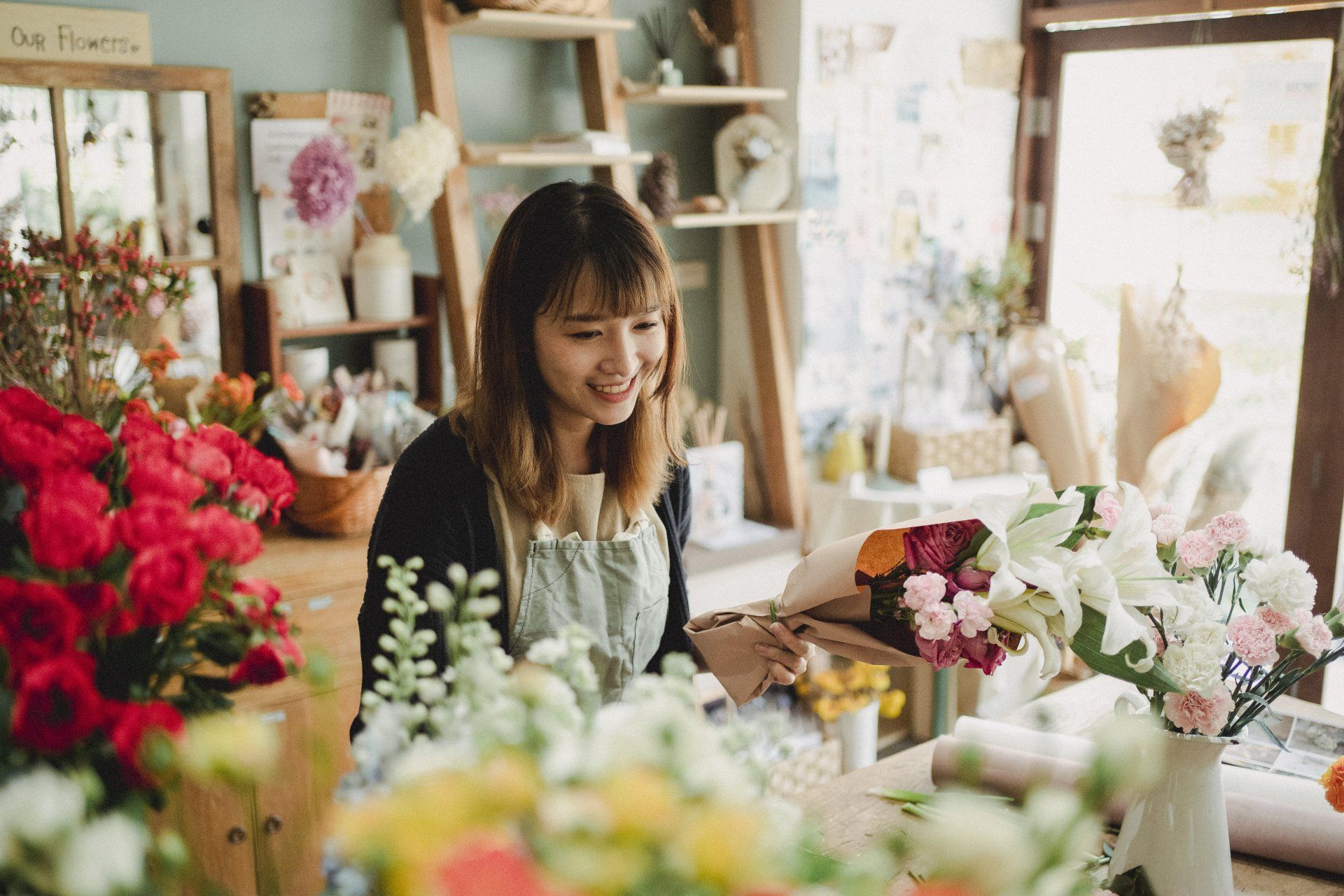 a woman is looking at flowers in a flower shop .