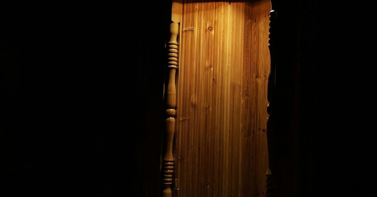 A wooden door is open to a dark room.