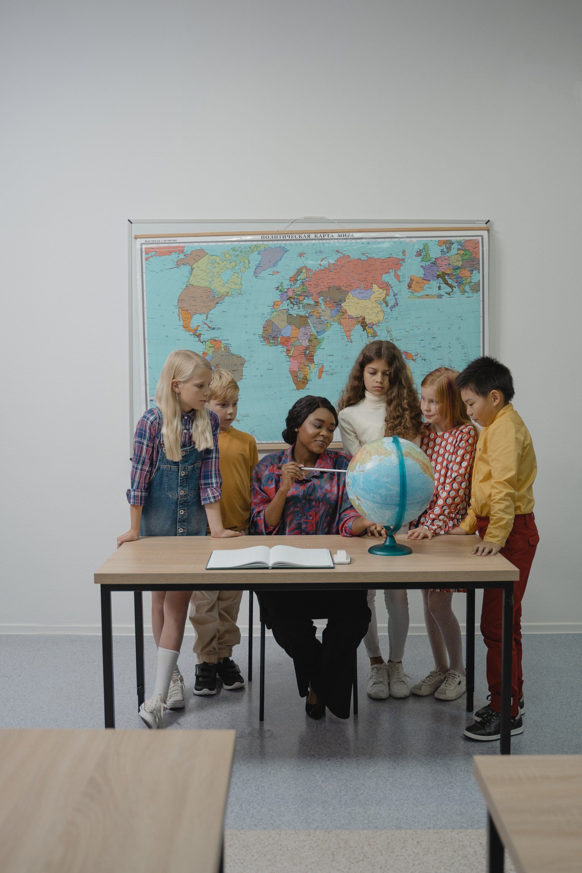 A group of children are looking at a globe in a classroom.