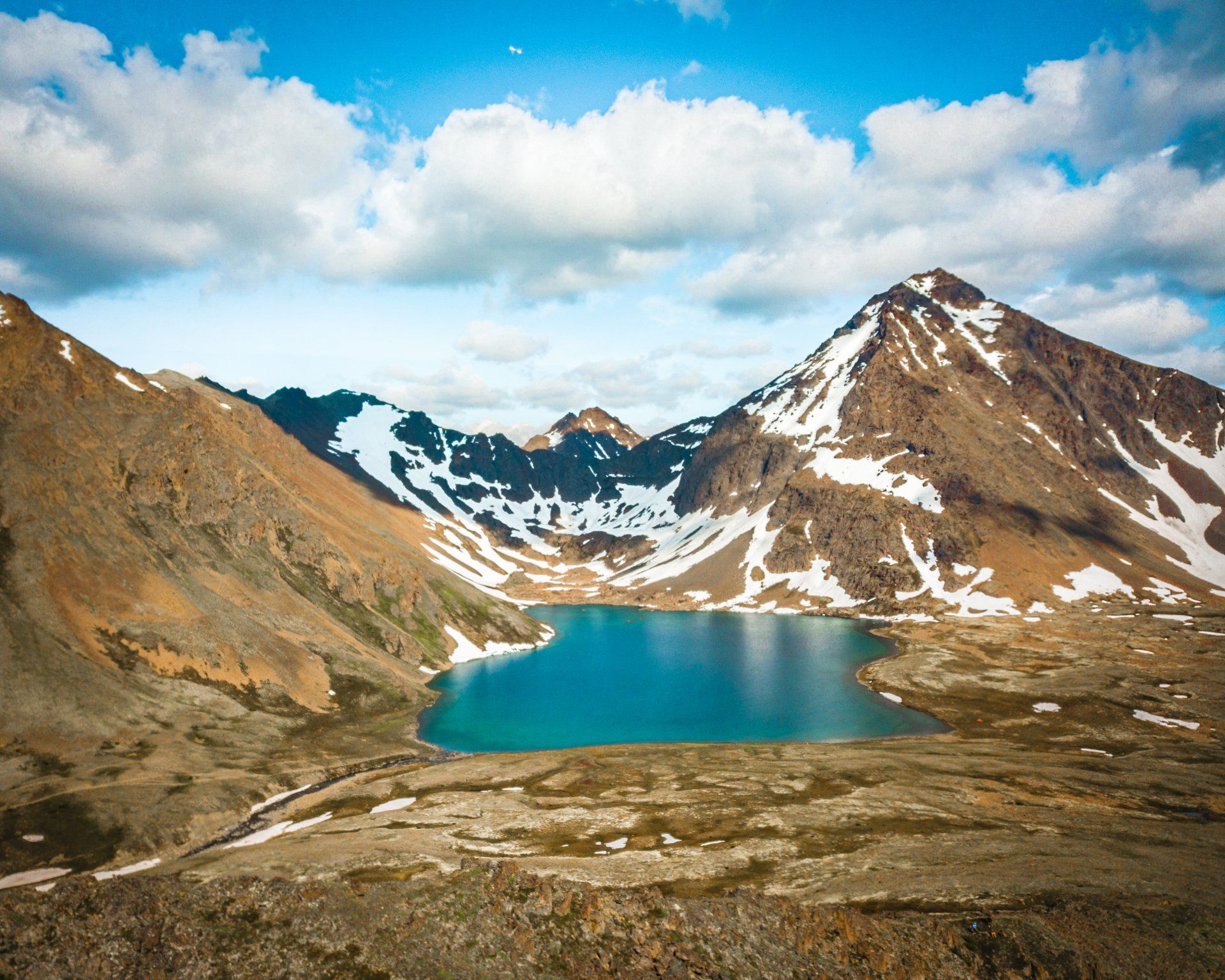 A lake surrounded by snow covered mountains on a cloudy day