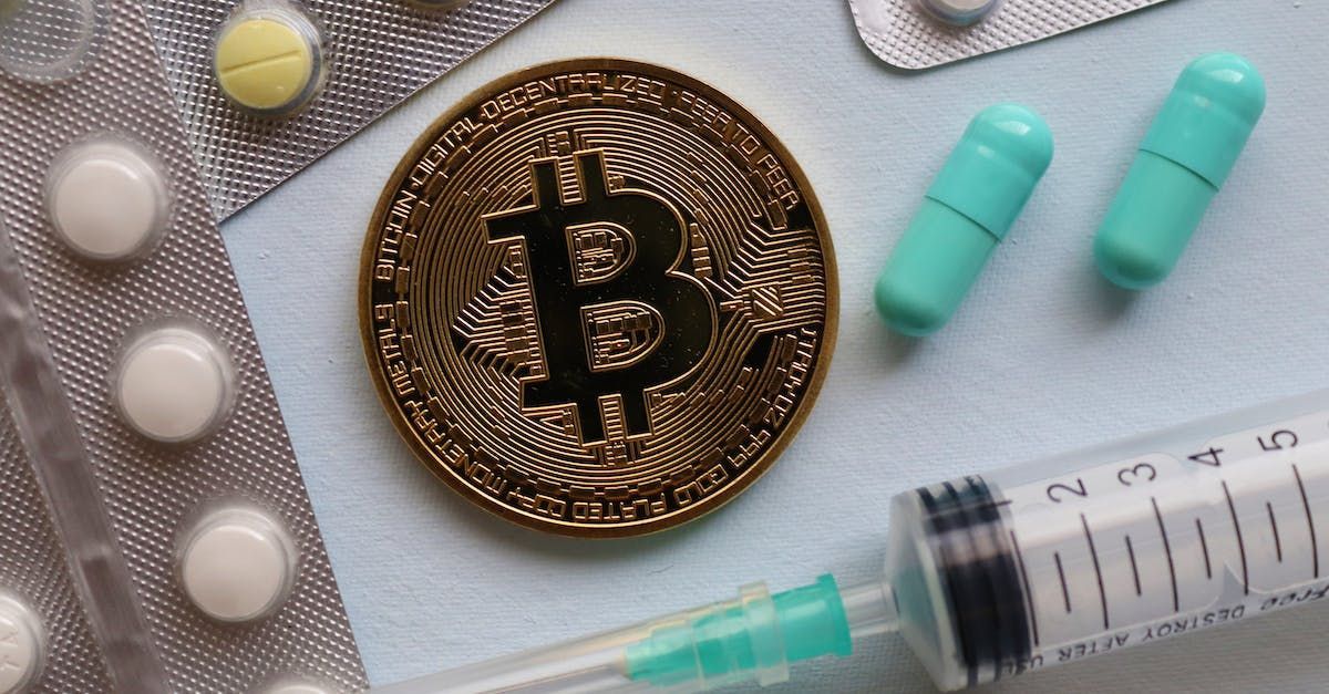 A bitcoin is sitting on a table next to a syringe and pills.