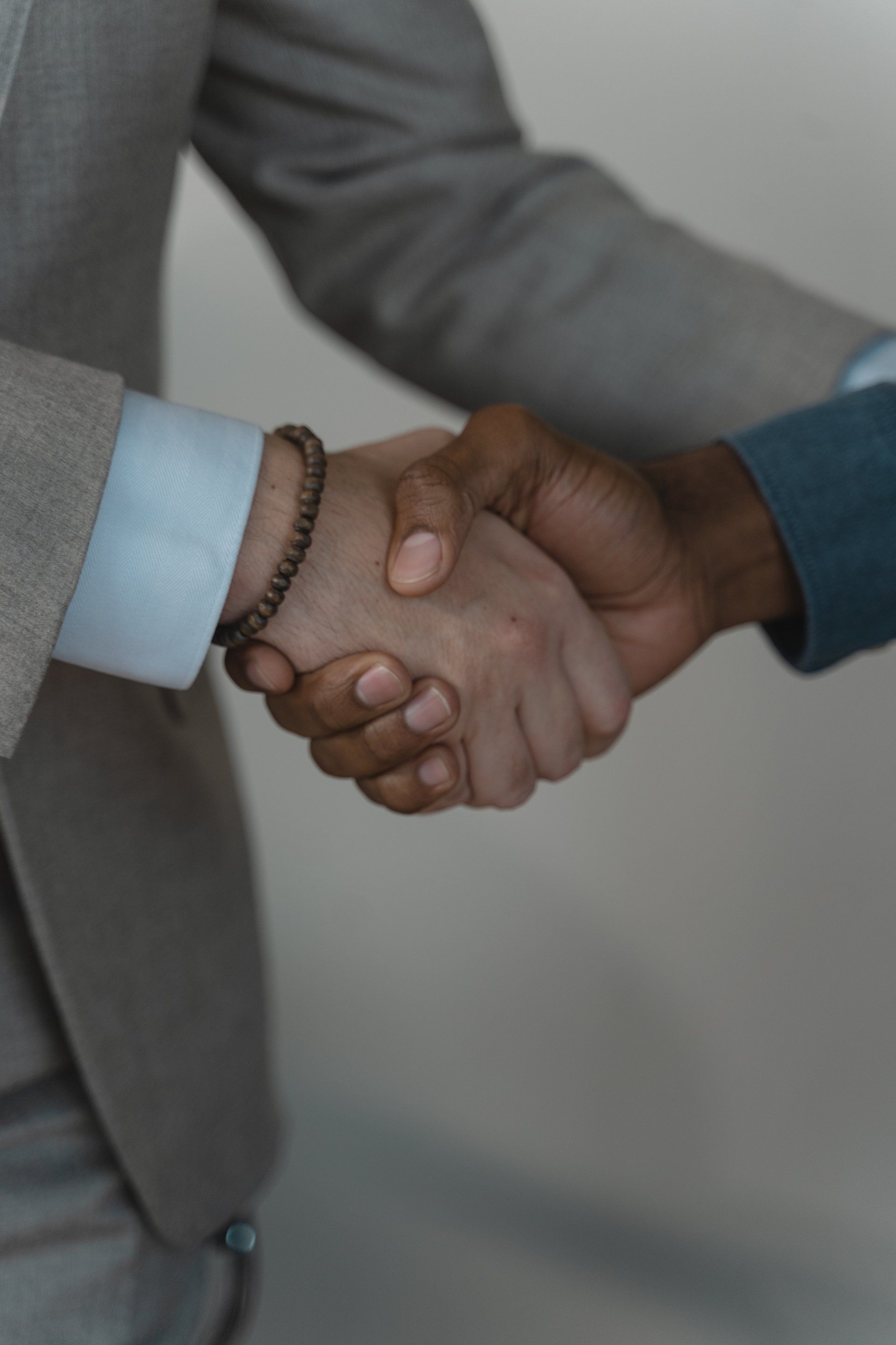 A man in a suit and a woman in a blue shirt are shaking hands.