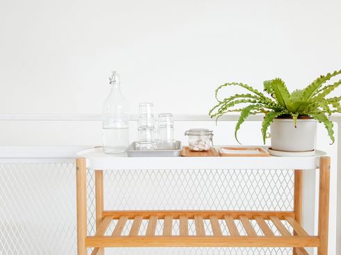 A wooden shelf with a potted plant and glasses on it.