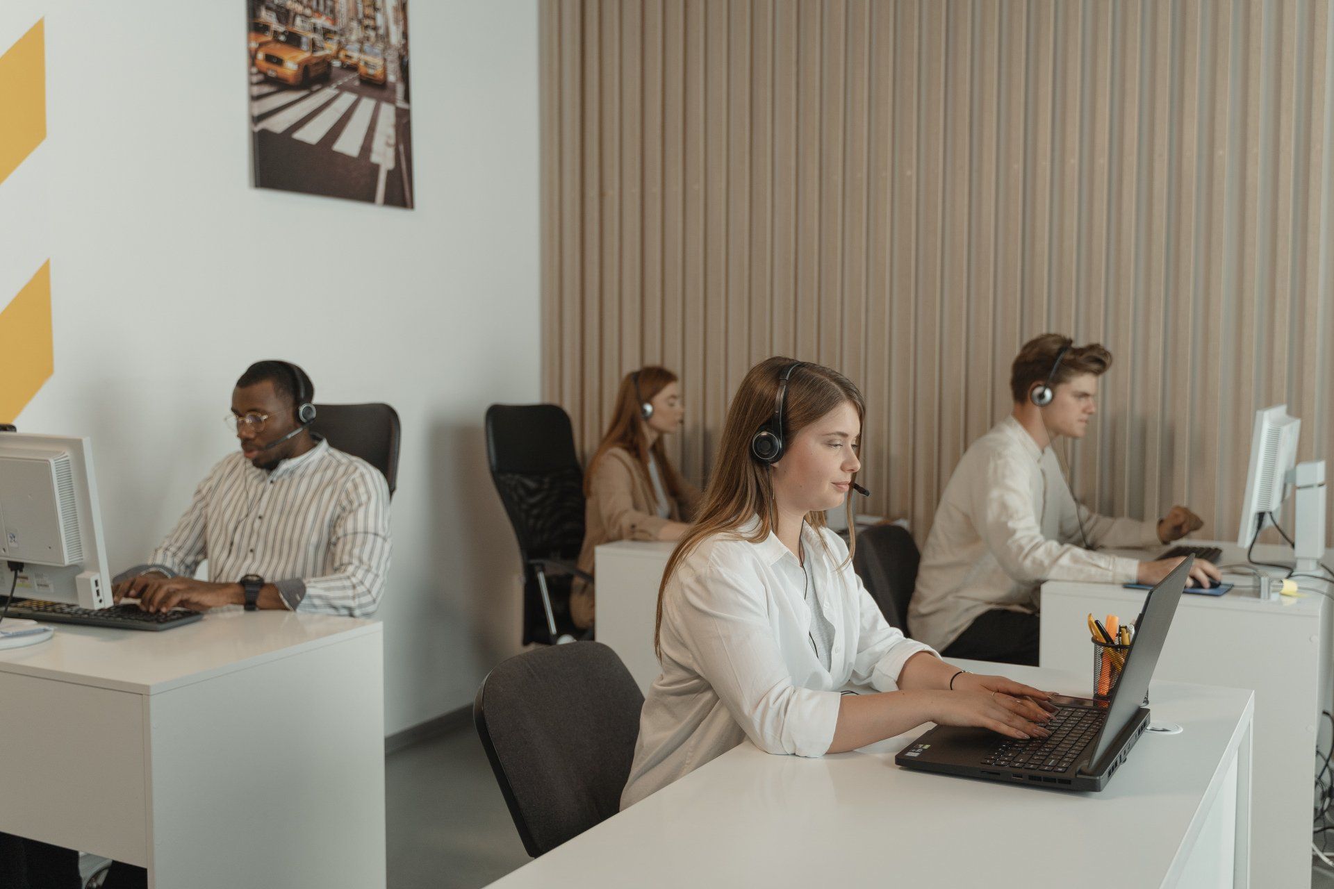 a group of people are sitting at desks in front of computers in a call center .