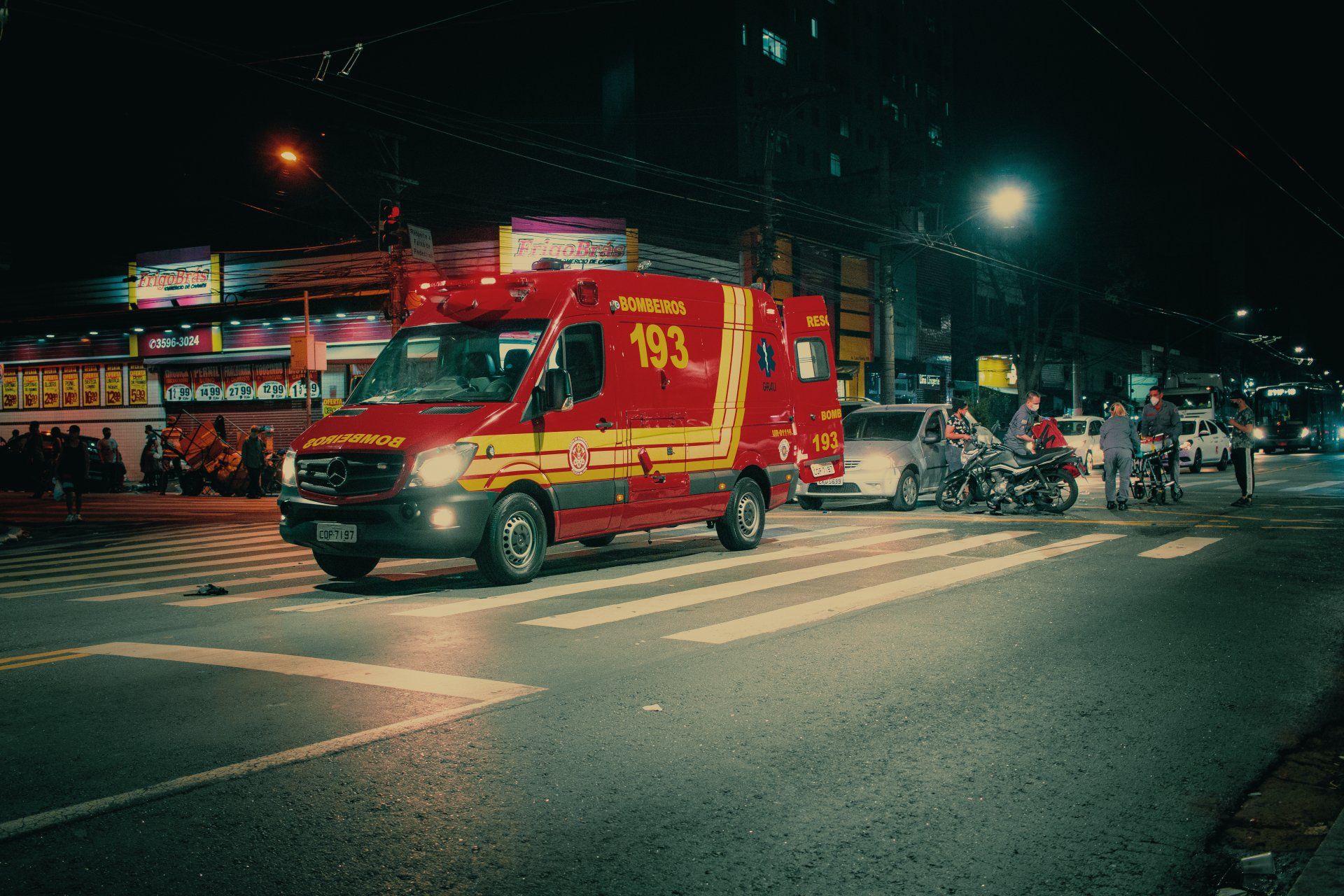 An ambulance is driving down a city street at night.