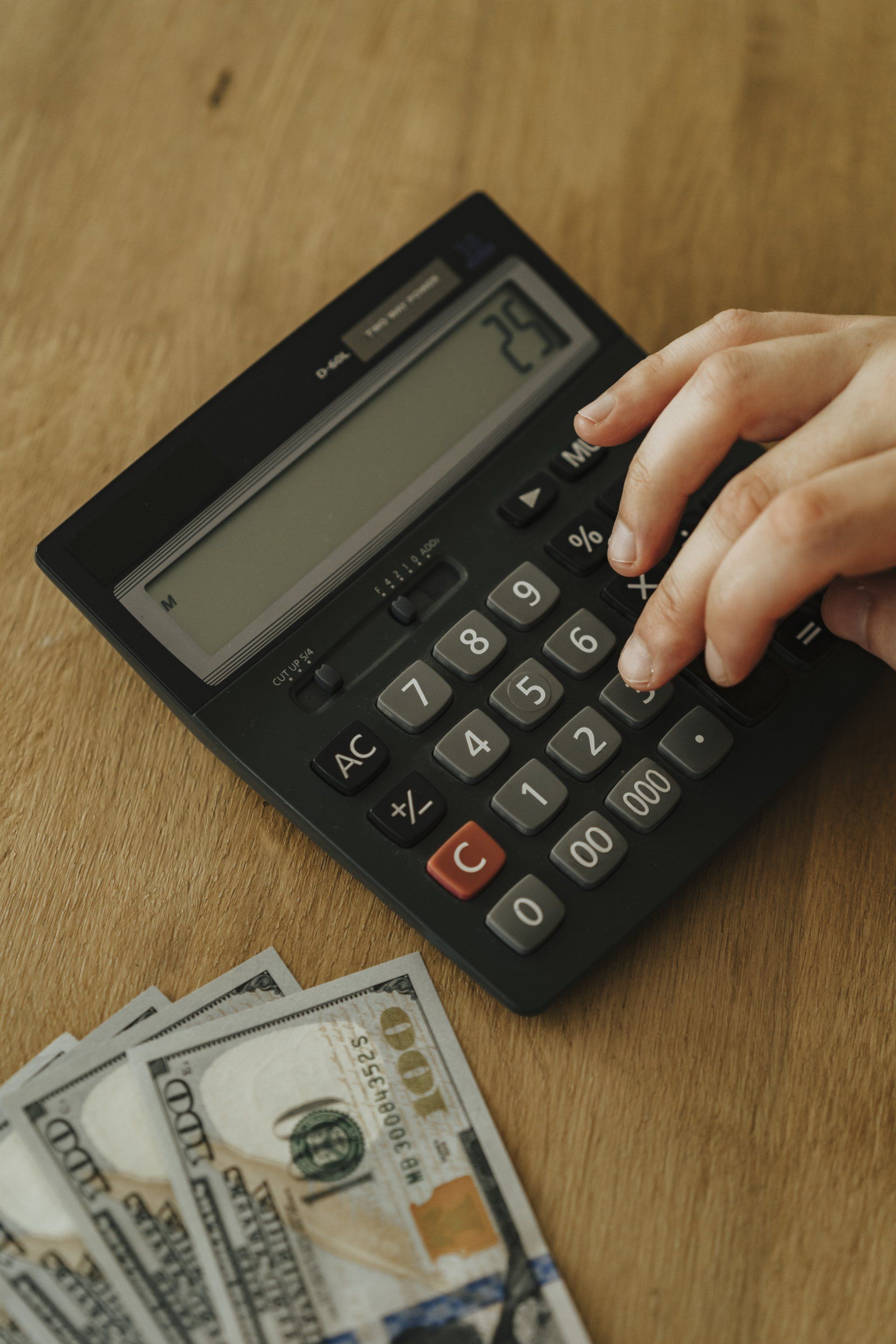 a person is using a calculator next to a pile of money .