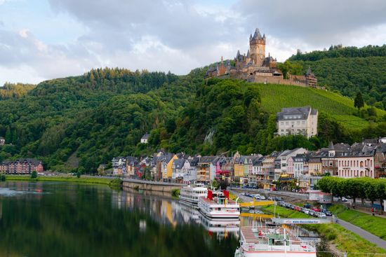 A castle is sitting on top of a hill next to a river.