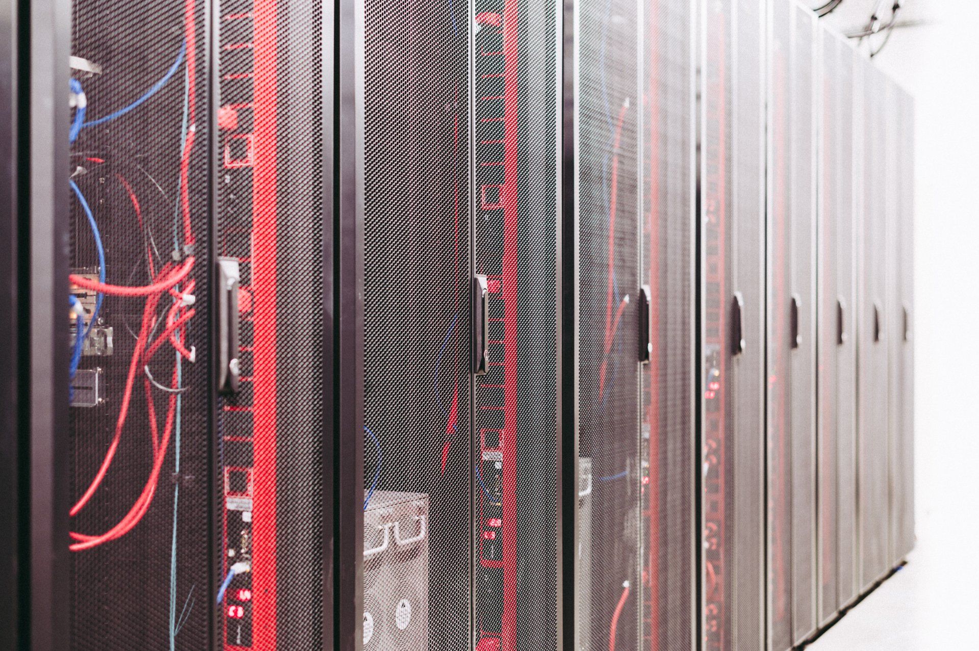 A row of servers in a data center with red and blue wires coming out of them.