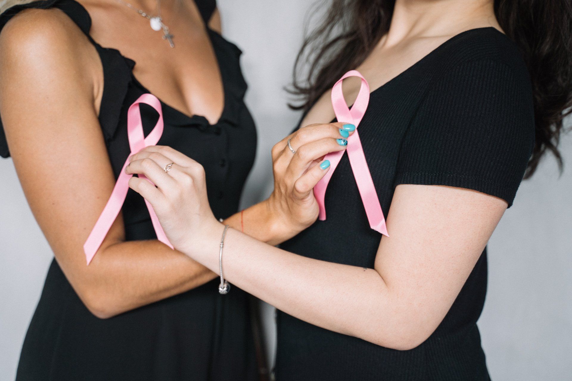 Deux femmes tiennent des rubans roses sur leur poitrine.