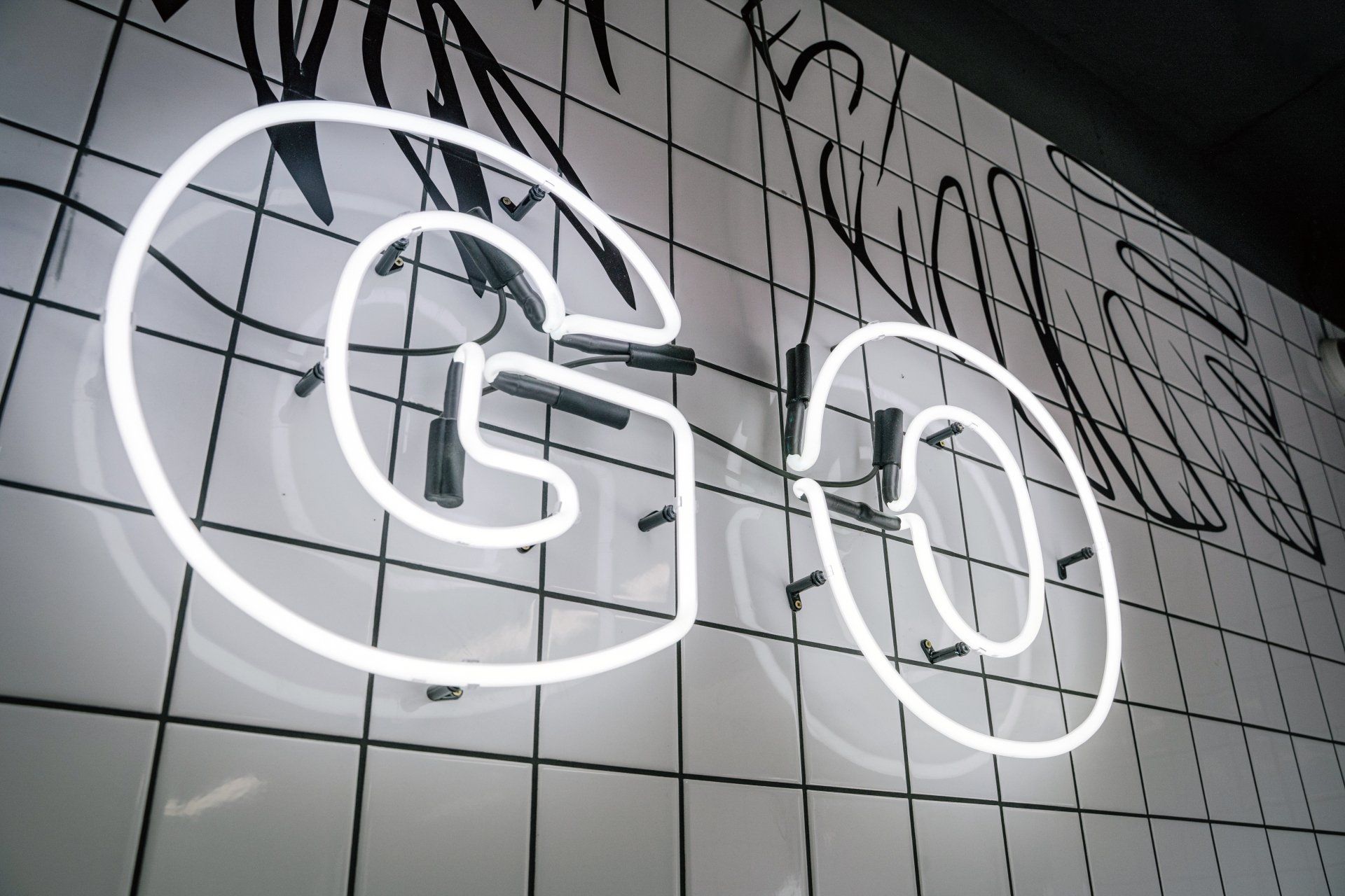 A neon sign that says go on a tiled wall