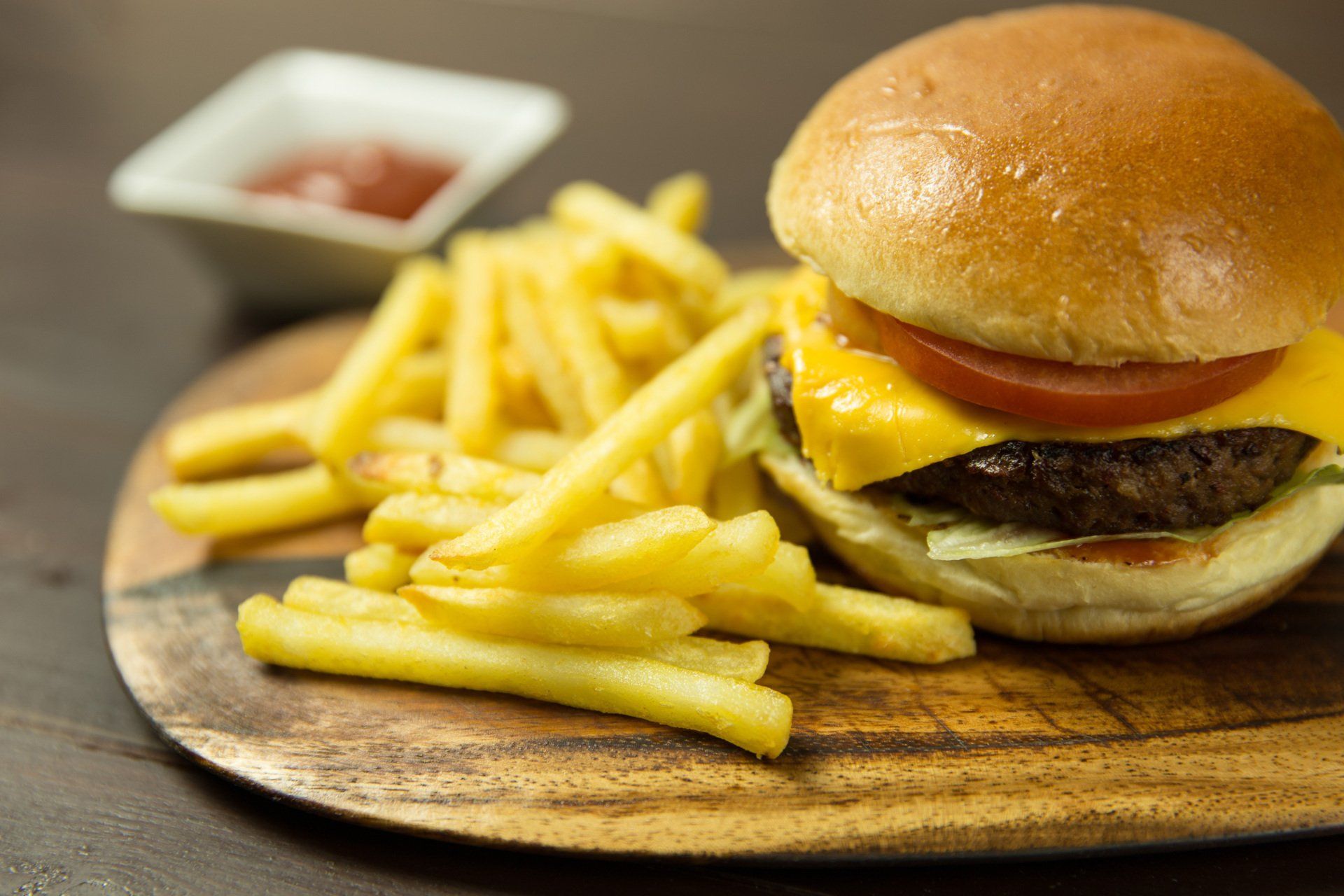 A hamburger and french fries on a wooden cutting board.