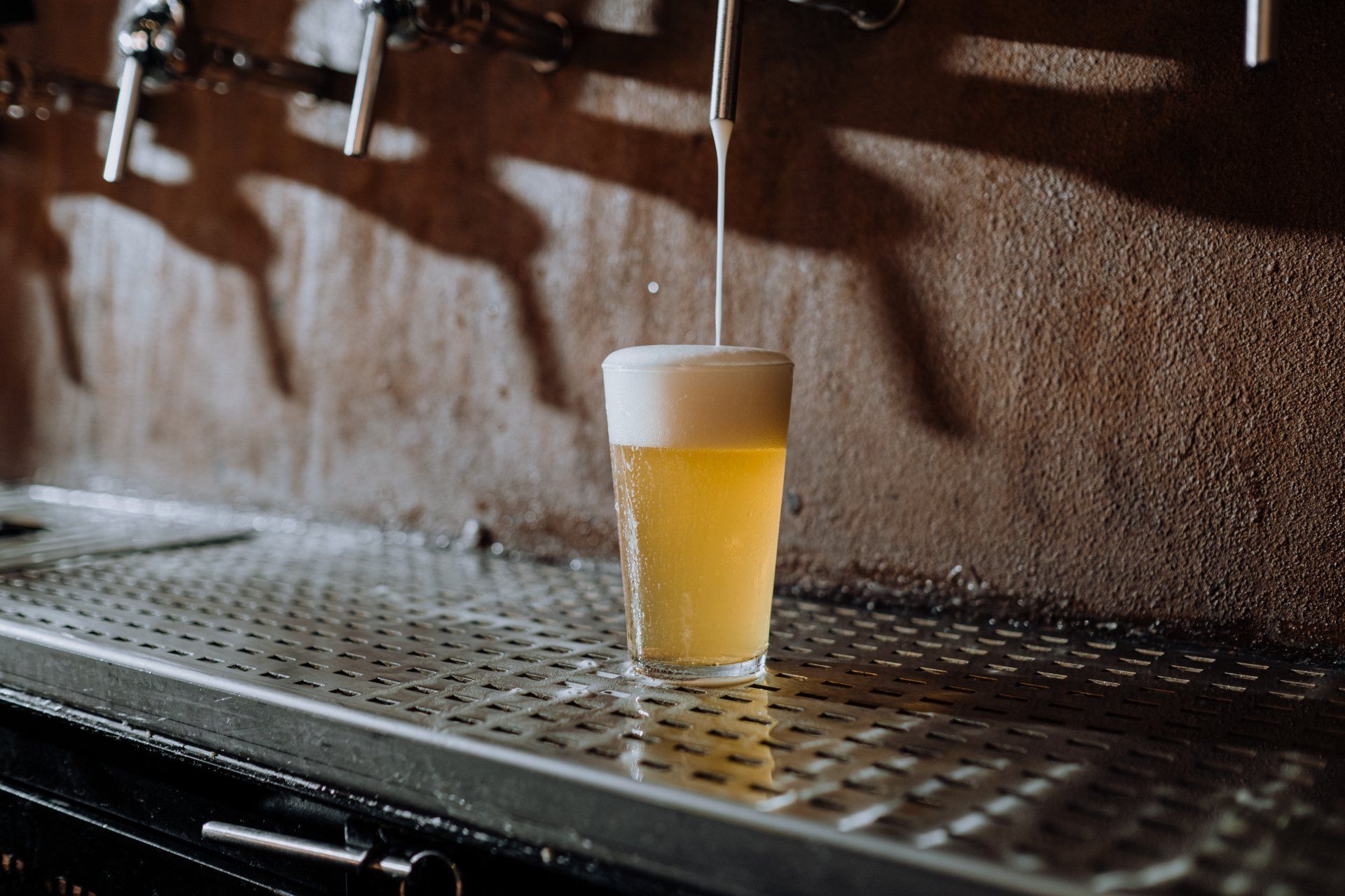 a glass of beer is being poured from a tap .