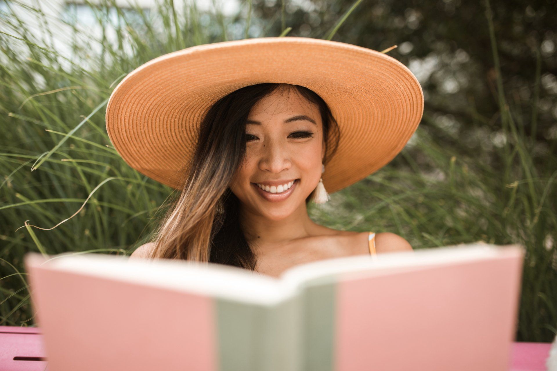 A woman wearing a hat is reading a book on how to purchase a home in Santa Cruz.