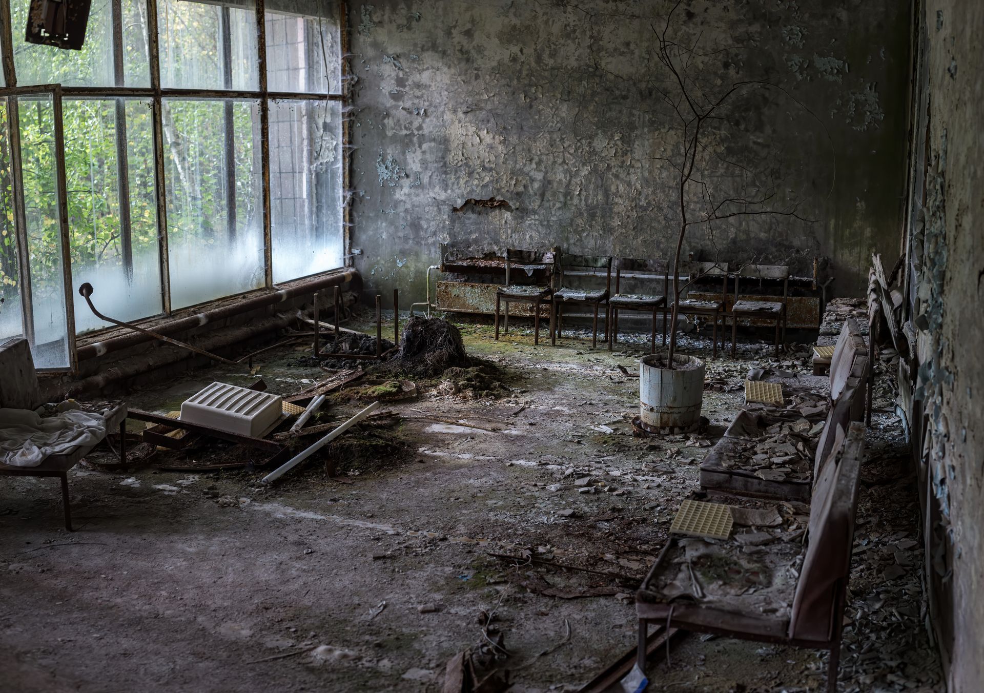 An abandoned room with a lot of chairs and a large window.