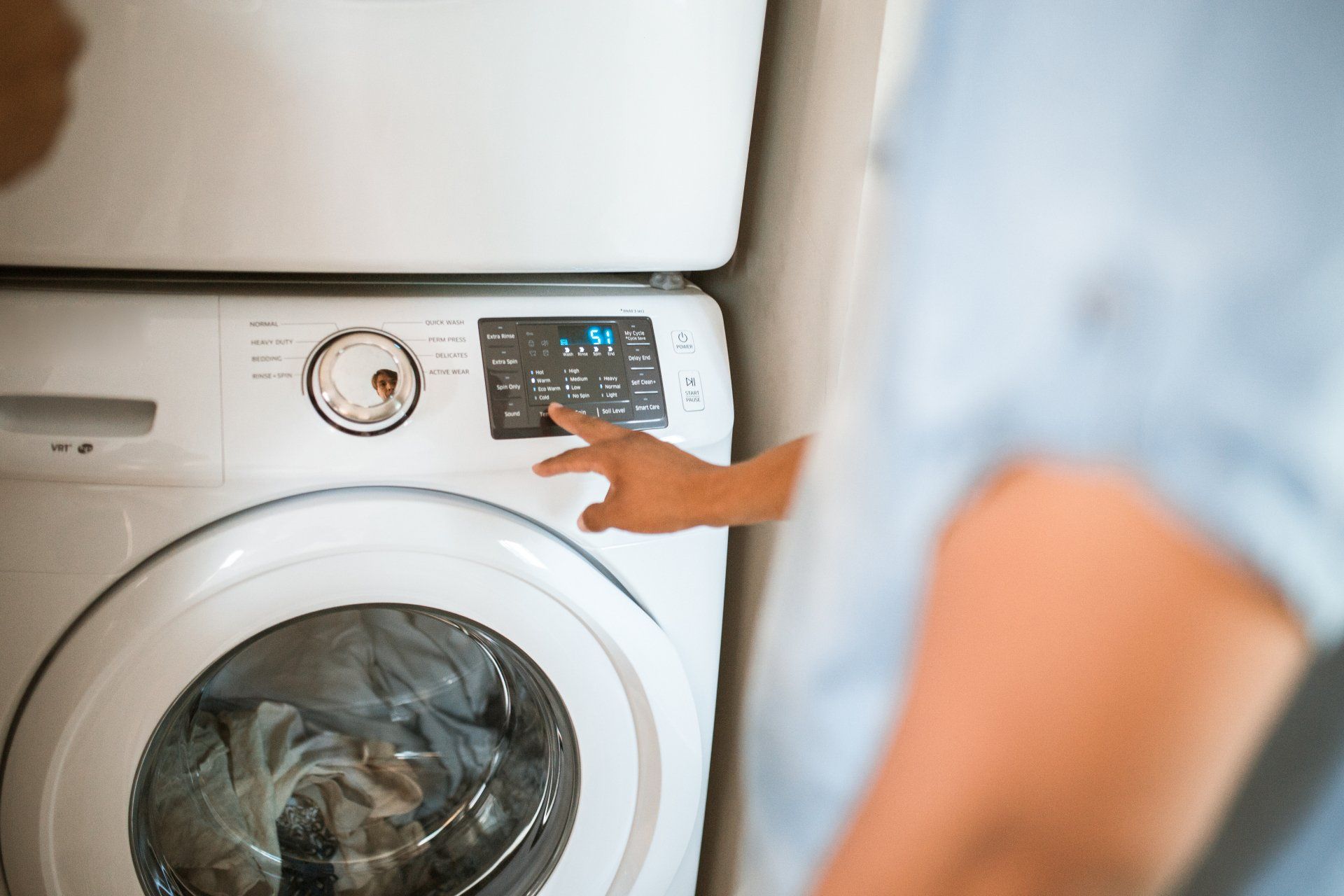 a person is pressing a button on a washing machine . Fresno appliance repair