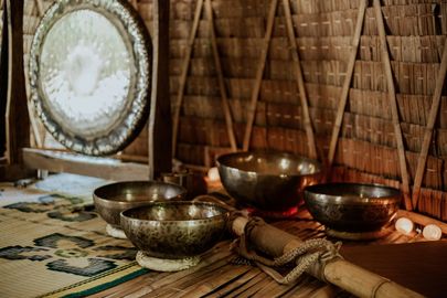 A group of singing bowls sitting on top of a bamboo mat in a room.