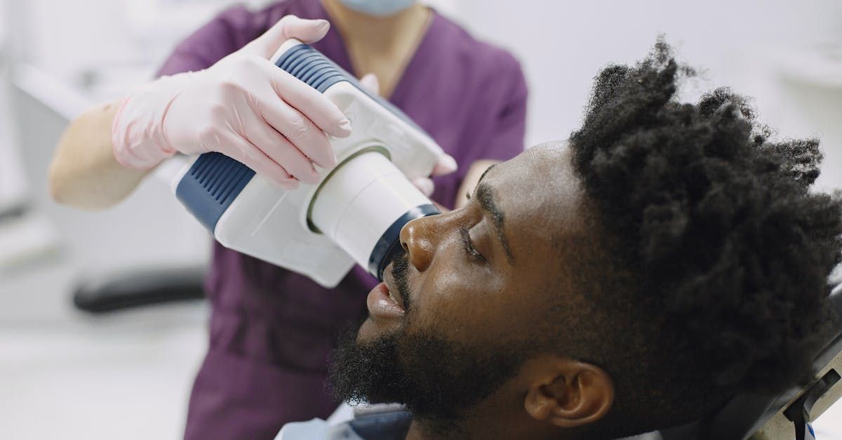 A man is getting an x-ray of his teeth by a dentist.