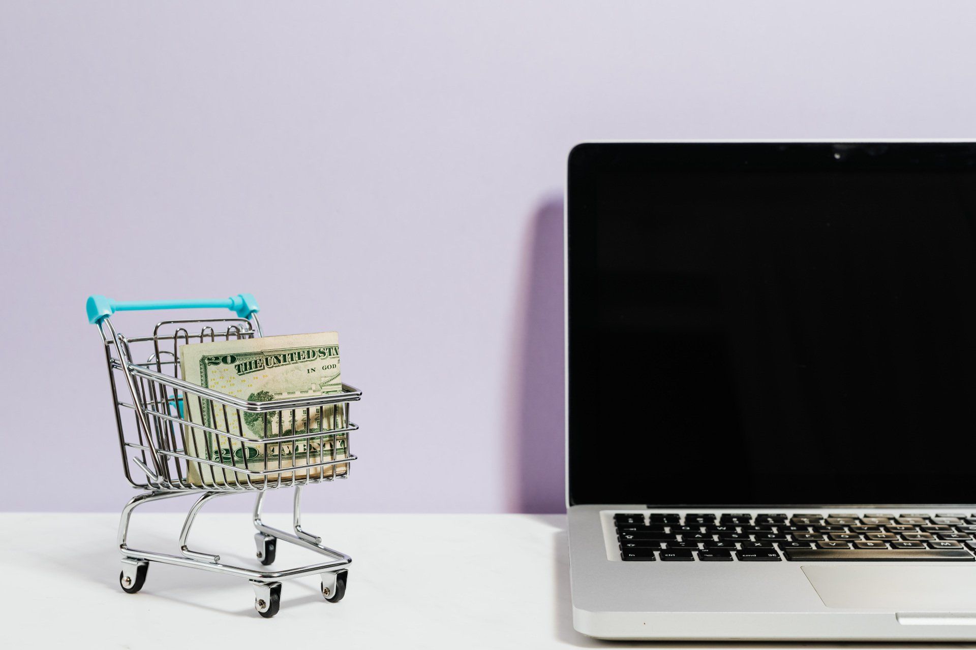 Shopping cart filled with money and laptop computer