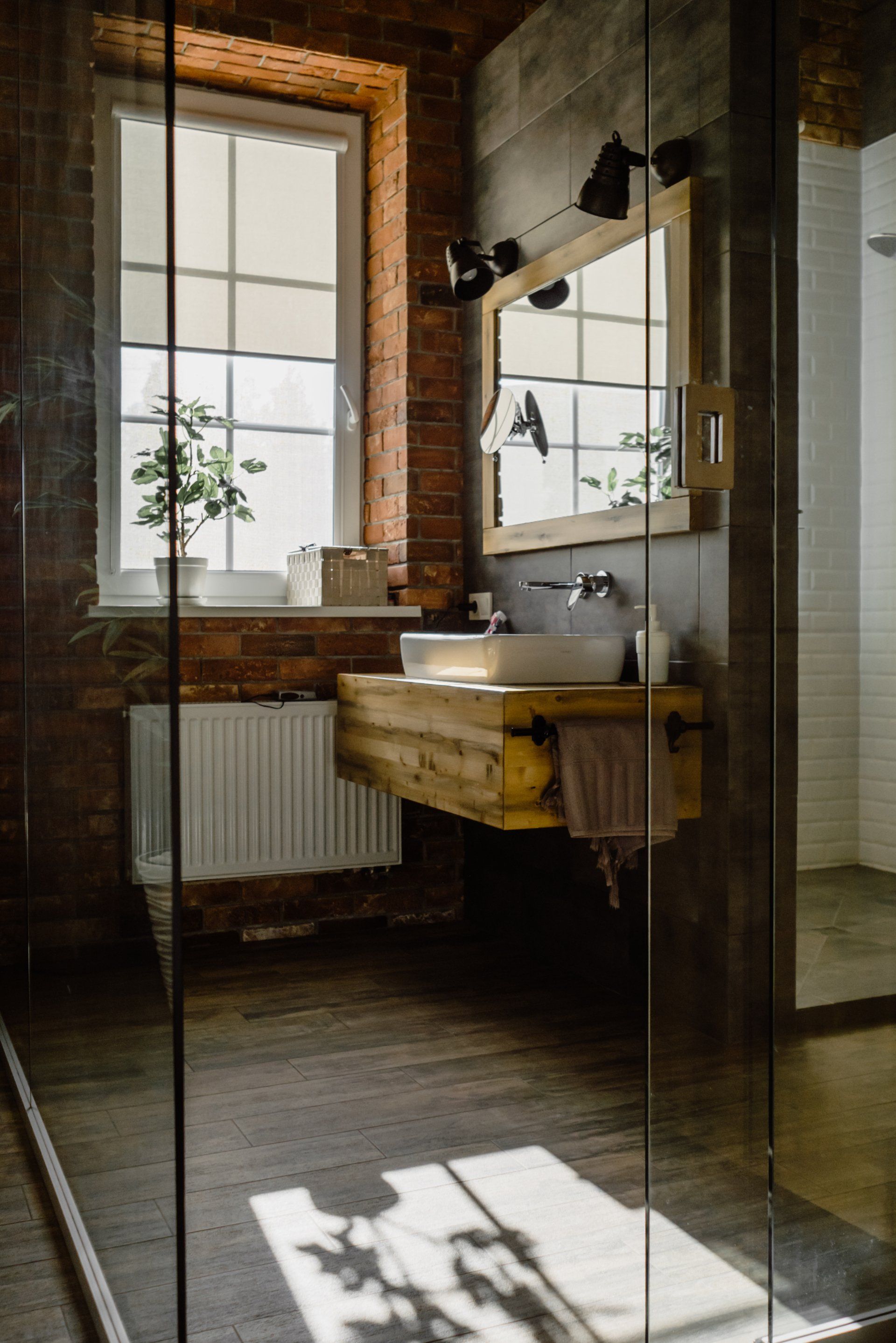 A bathroom with a sink , mirror and window.