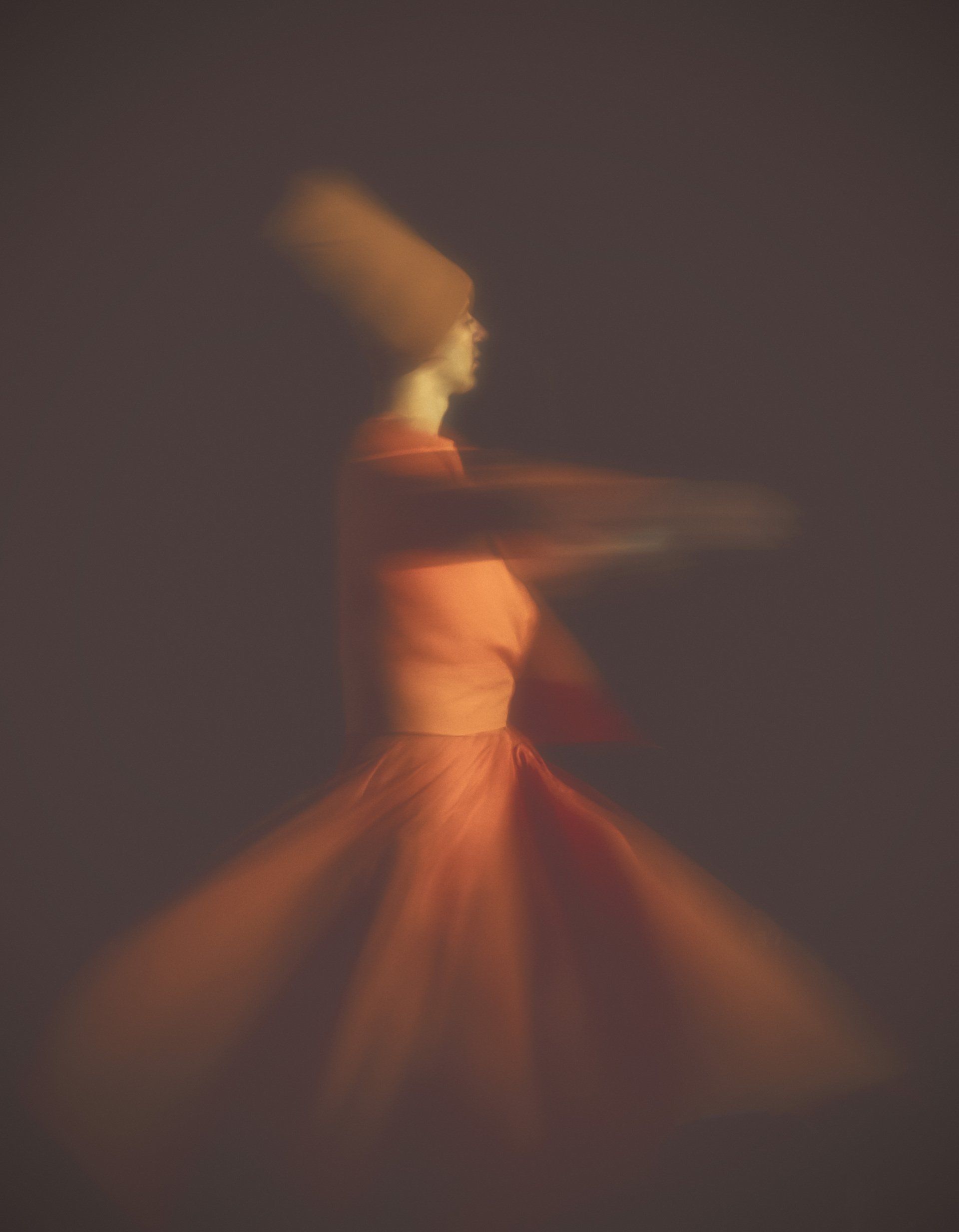 A blurry picture of a woman in a red dress dancing.