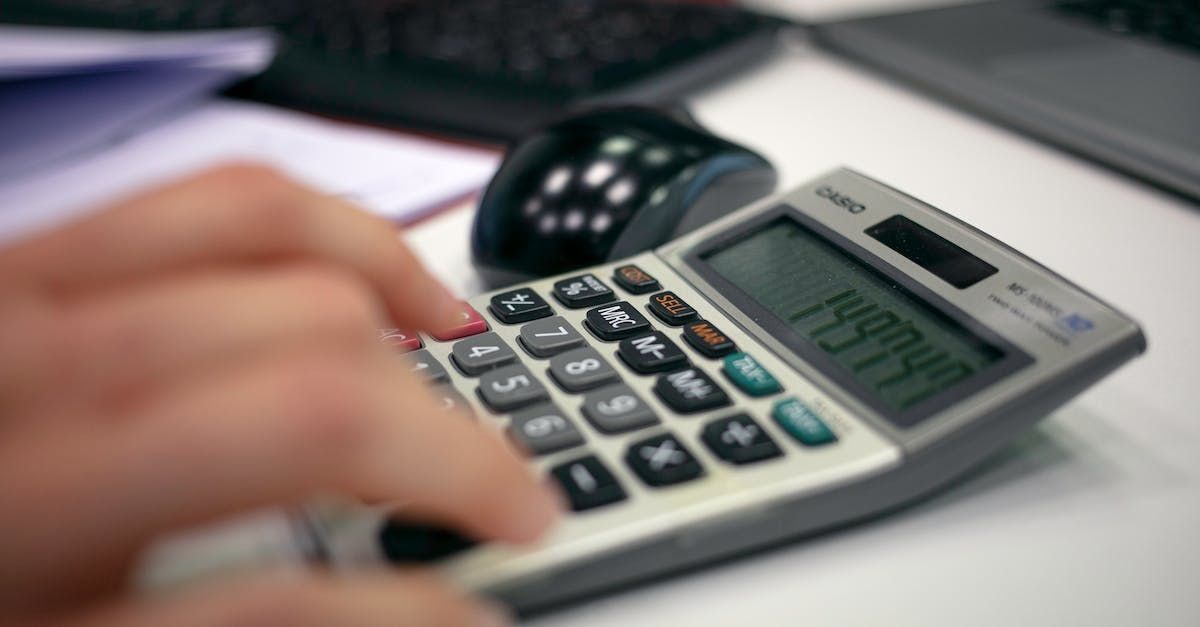 Una persona está escribiendo en una calculadora con un mouse en segundo plano.