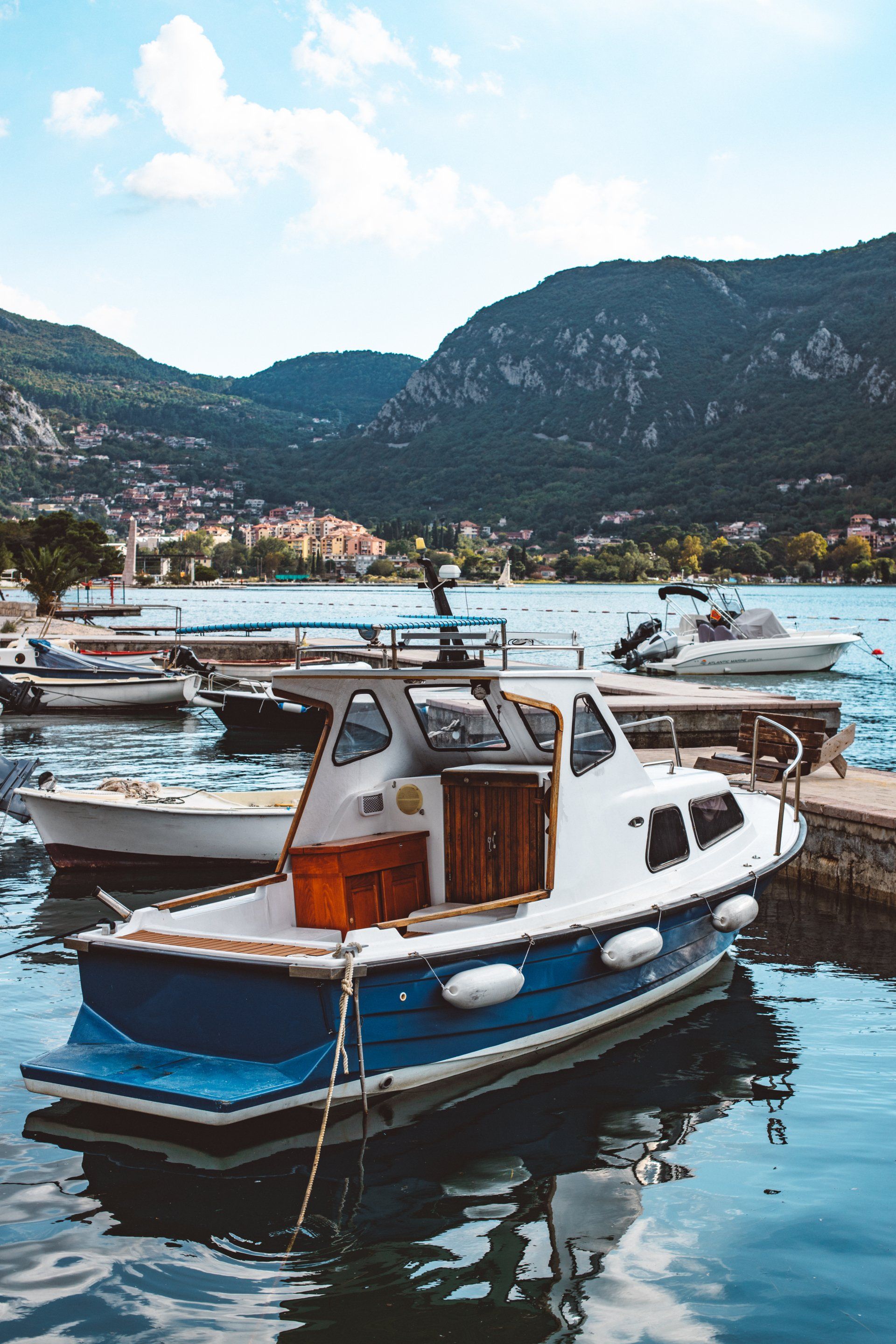 A group of boats are docked in a harbor with mountains in the background.