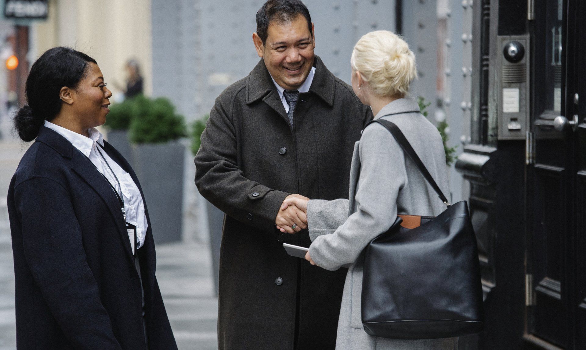 A man and a woman are shaking hands on a sidewalk