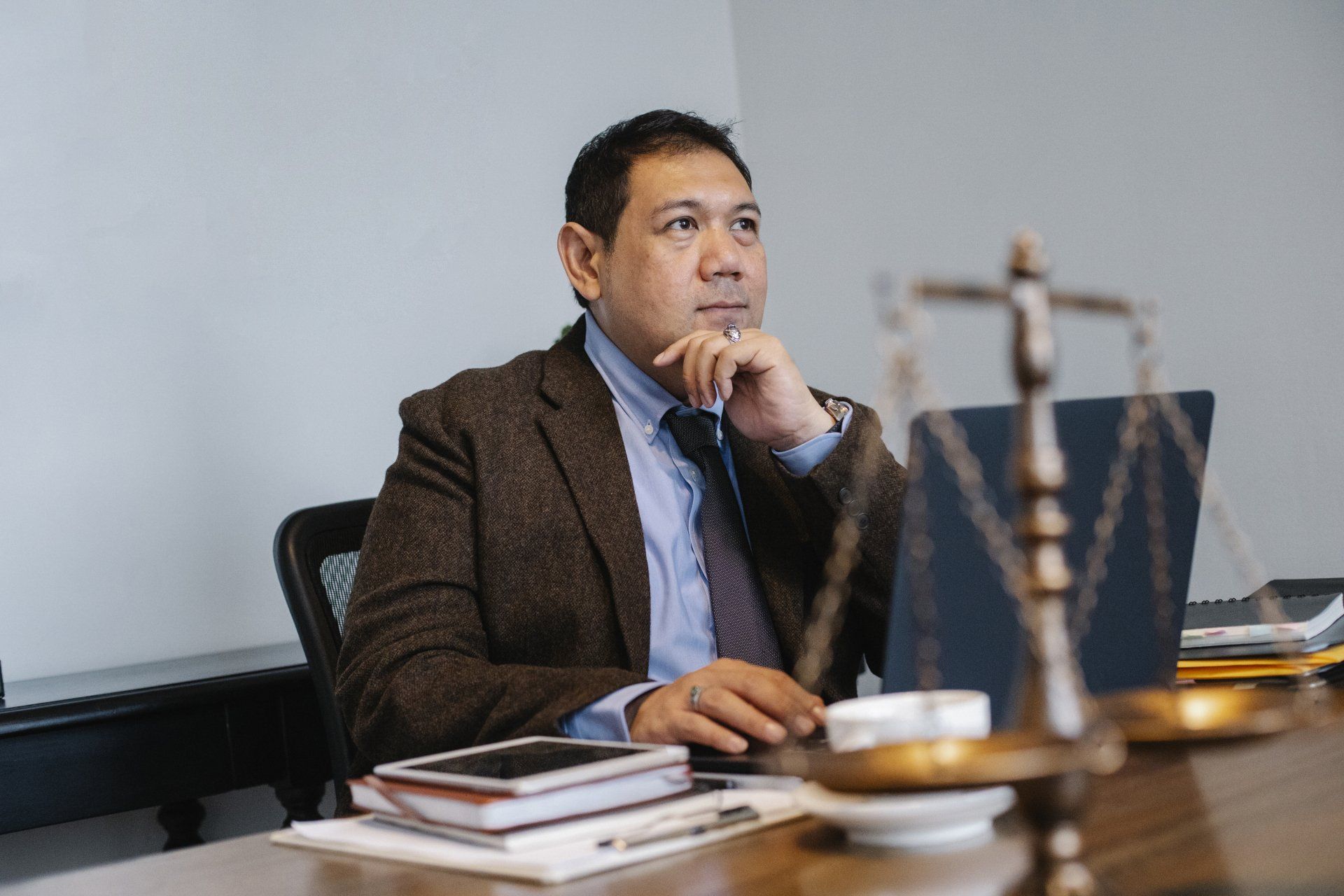 Man in a suit sitting at a desk thinking.