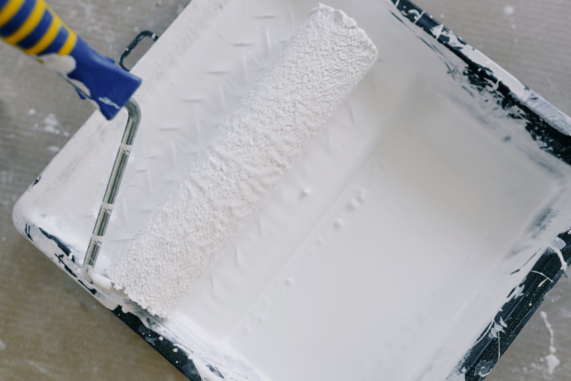 A picture of a roller tray filled with white paint by painters and decorators Southampton