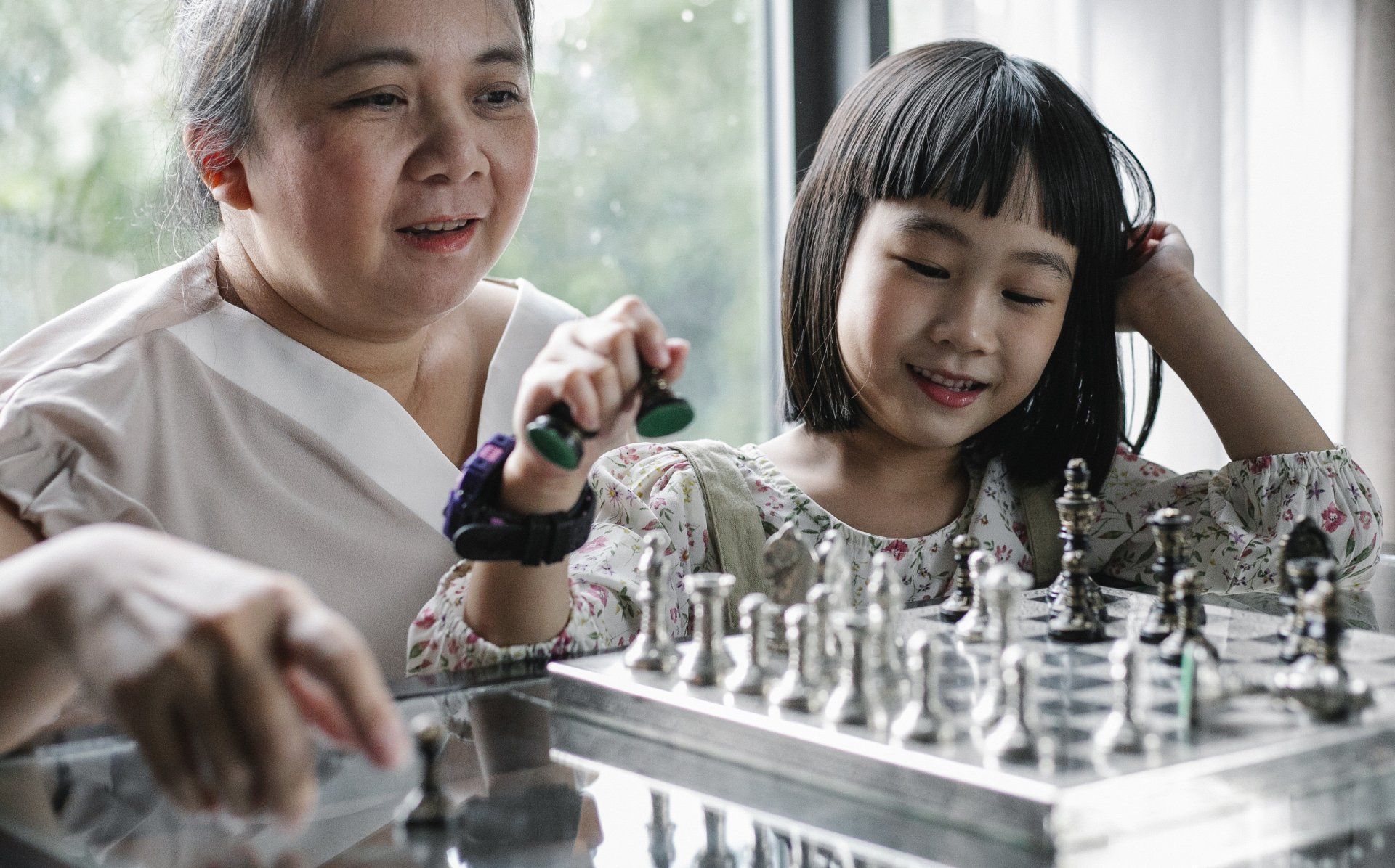 Woman helping girl child play chess