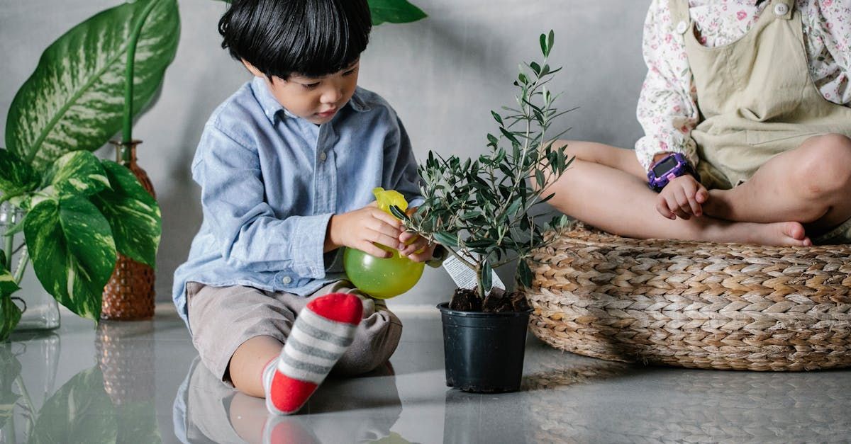 A boy and a girl are sitting on the floor watering plants.