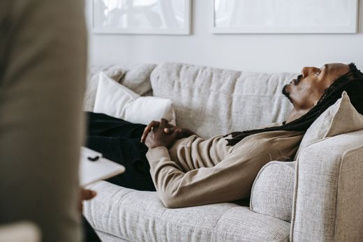 A man is sleeping on a couch in a living room.