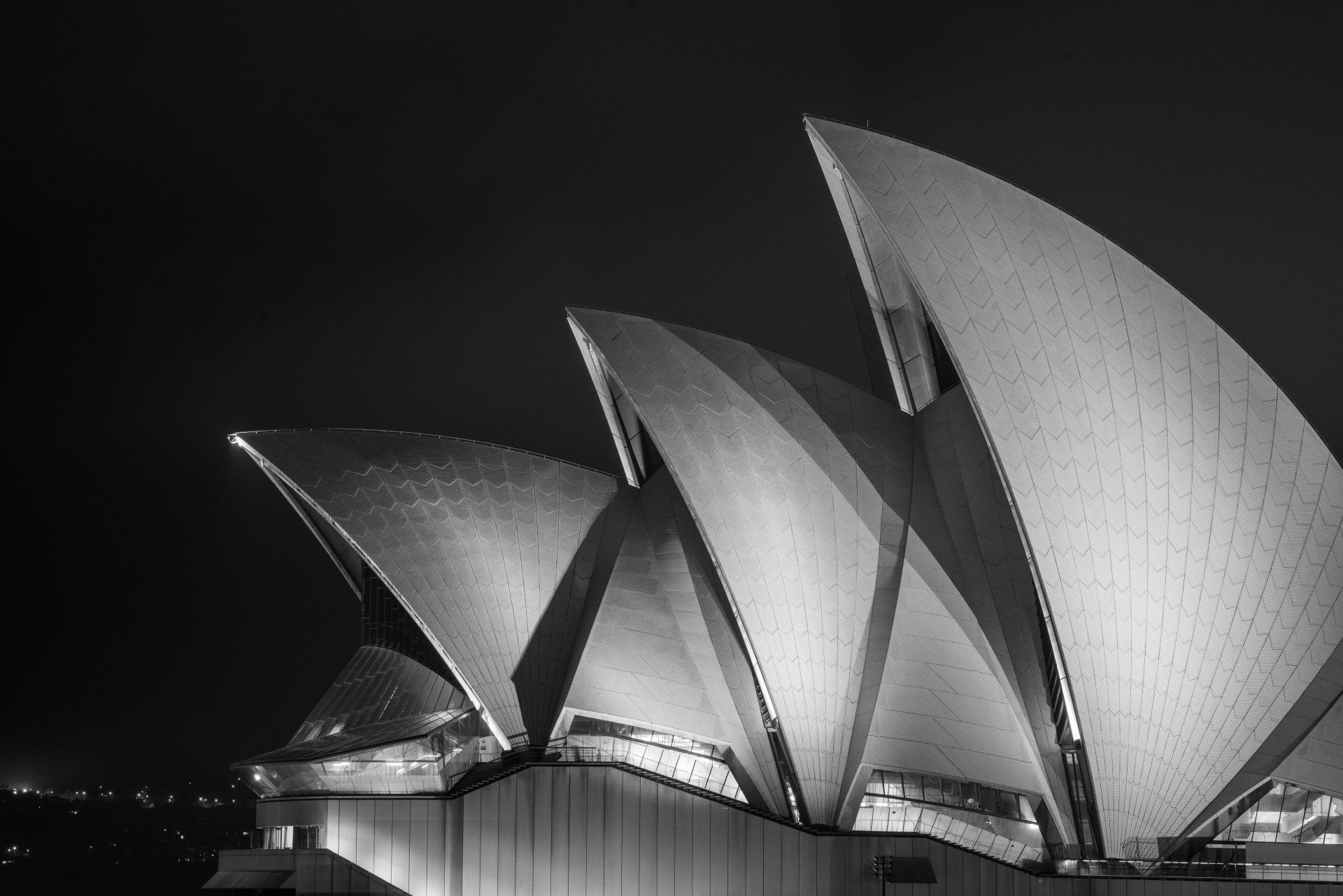 Ópera de Sydney à noite, iluminada, em preto e branco.