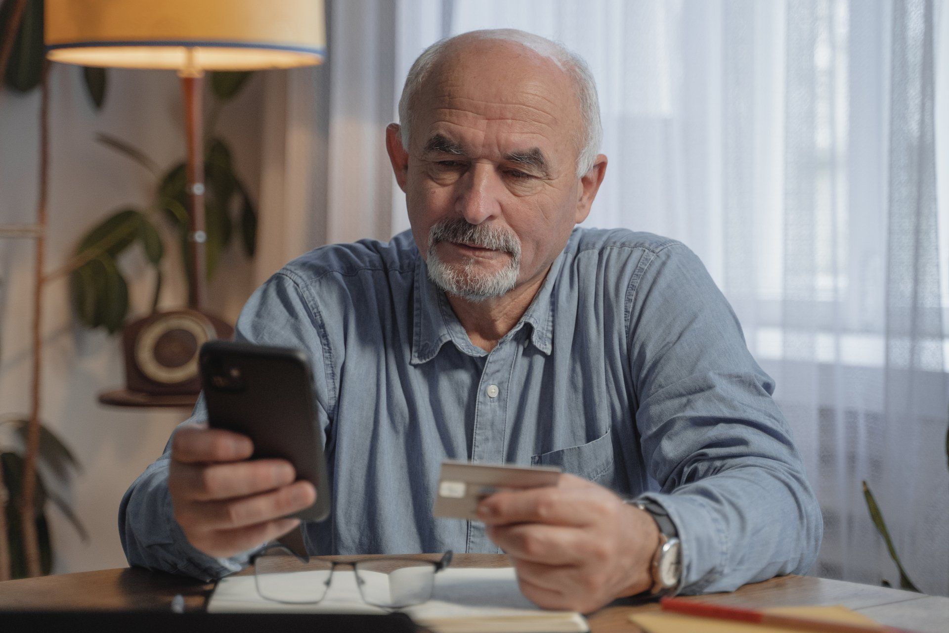 Senior Citizen holding phone and looking at credit card