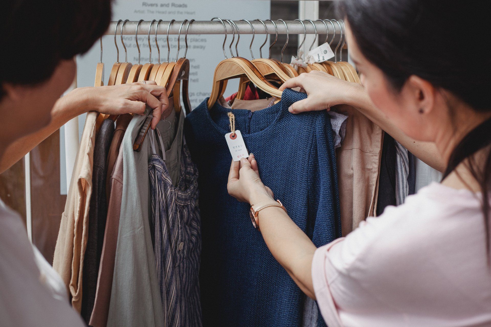 Two women are looking at clothes on a rack in a store.