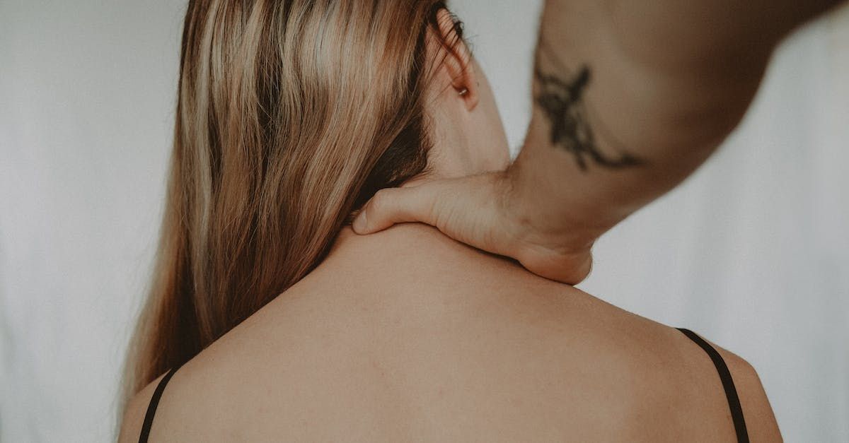 A woman is getting a massage from a man with a tattoo on his arm.