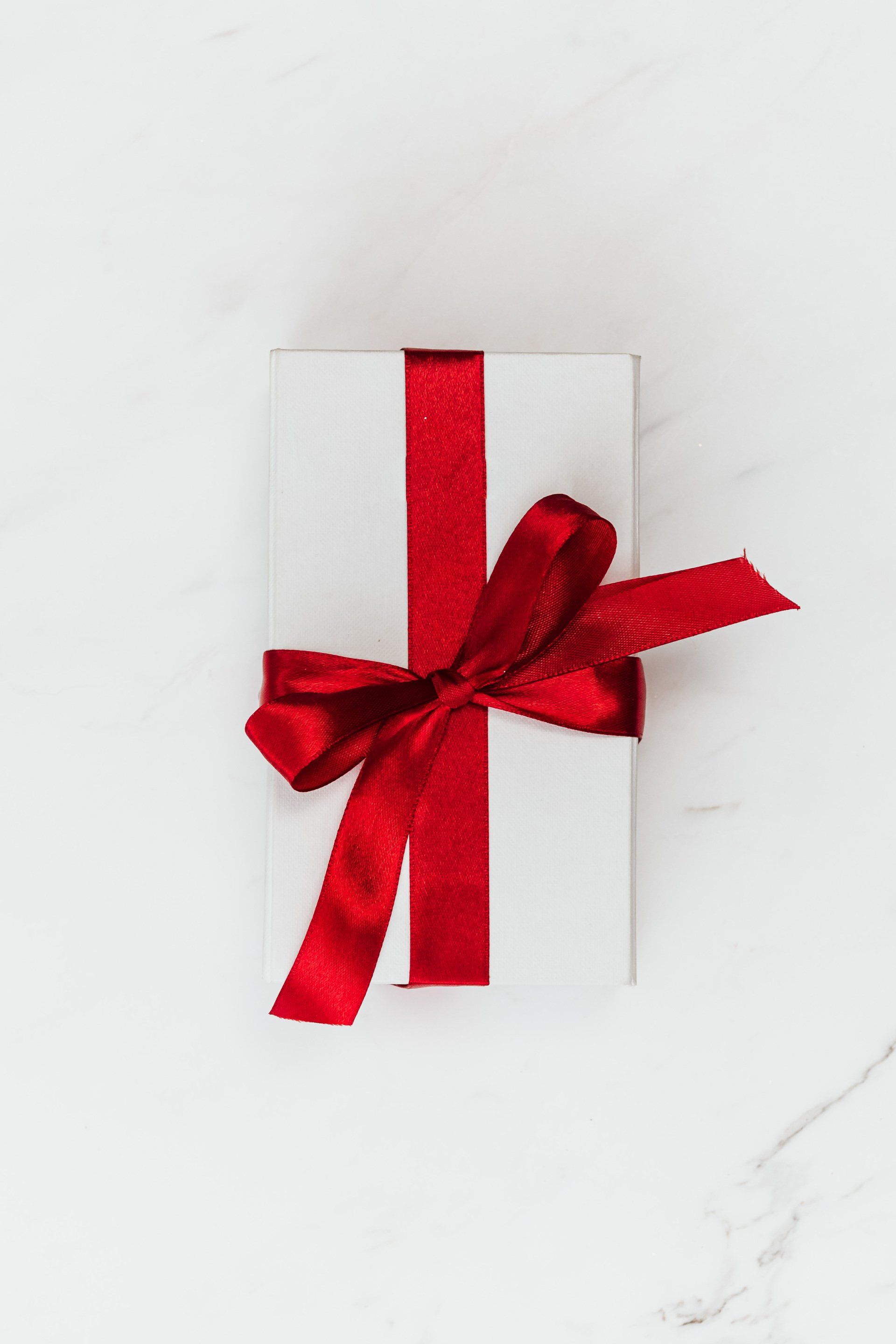 A white gift box with a red ribbon tied around it.